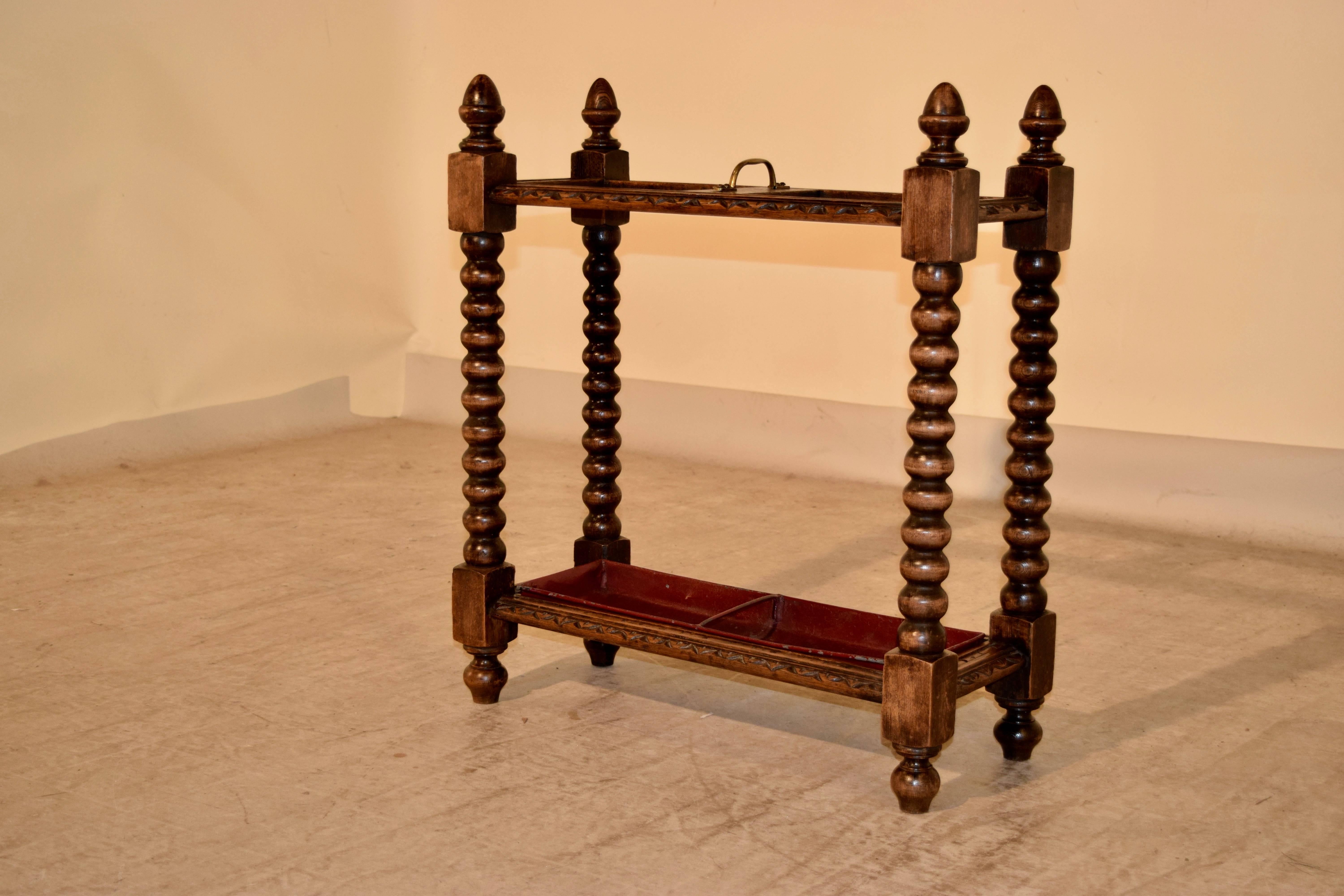 19th century English oak umbrella stand with carved decorated top following down to hand-turned spool legs, joined at the bottom by another turned molded base. Raised on turned feet.