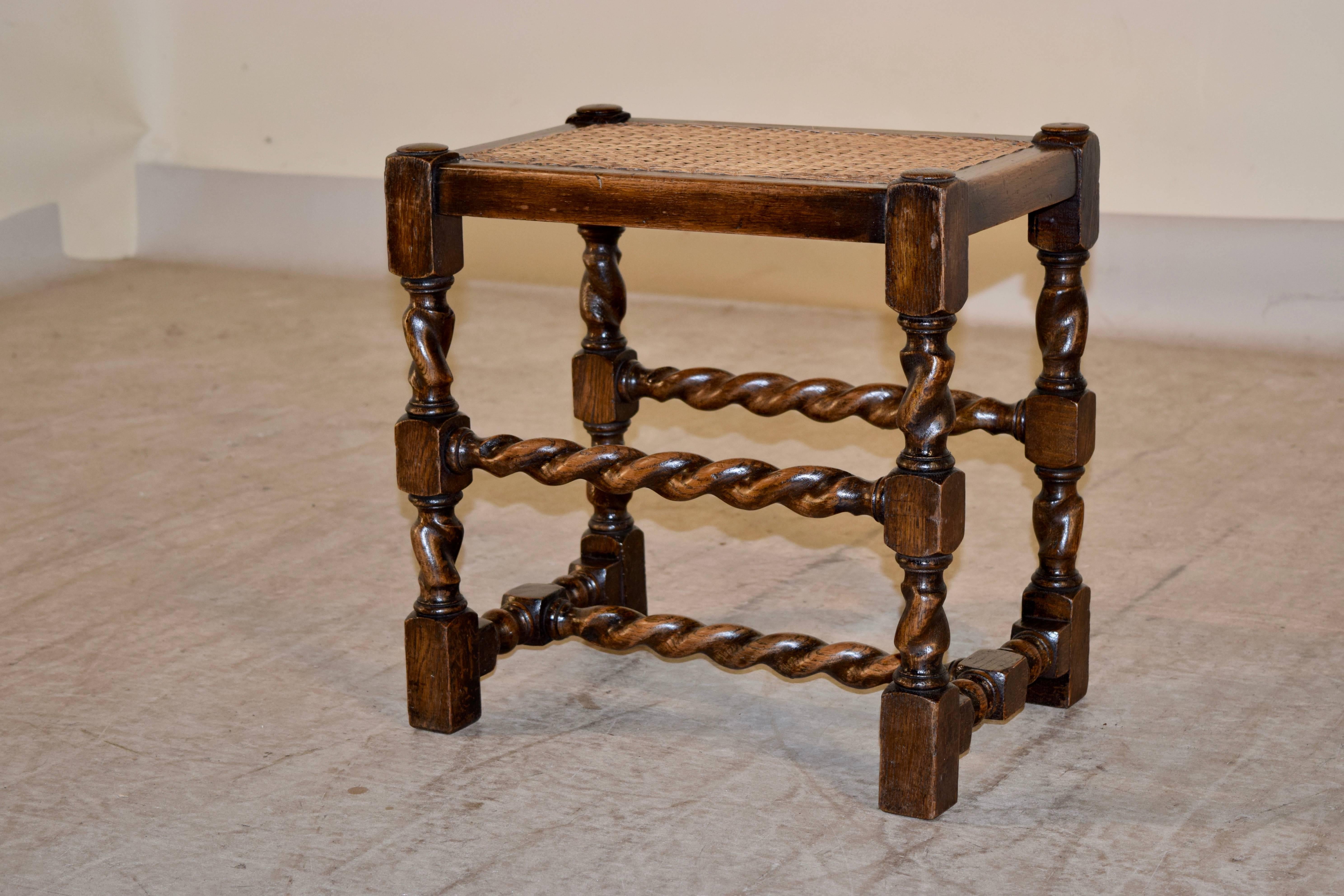 19th century English oak stool with hand-turned barley twist legs and stretchers and a woven cane top.