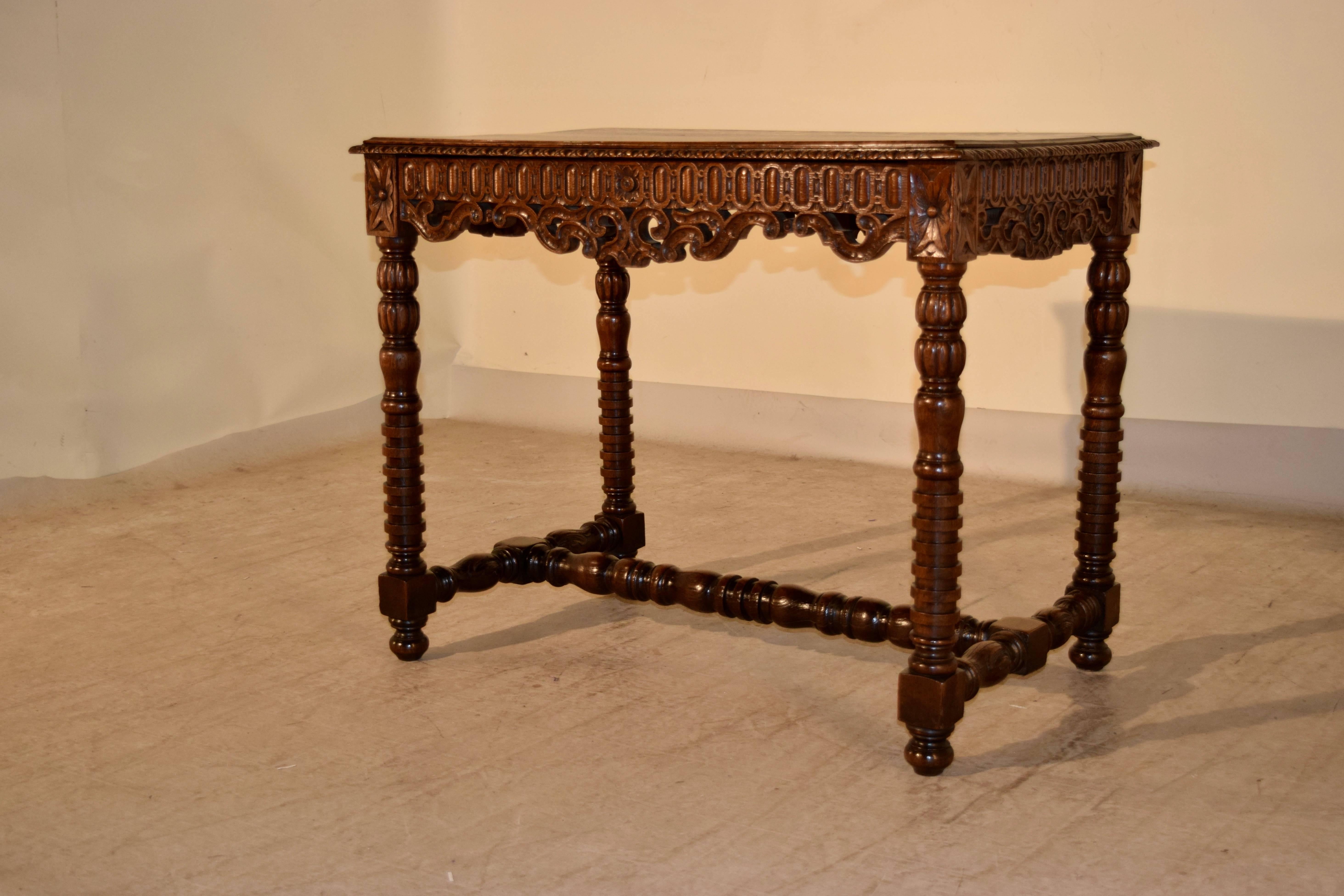 19th century French side table made from oak with a beveled and gadrooned edge around the top, following down to carved and pierced decorated aprons on three sides with a concealed drawer in the front. The piece is supported on hand-carved and