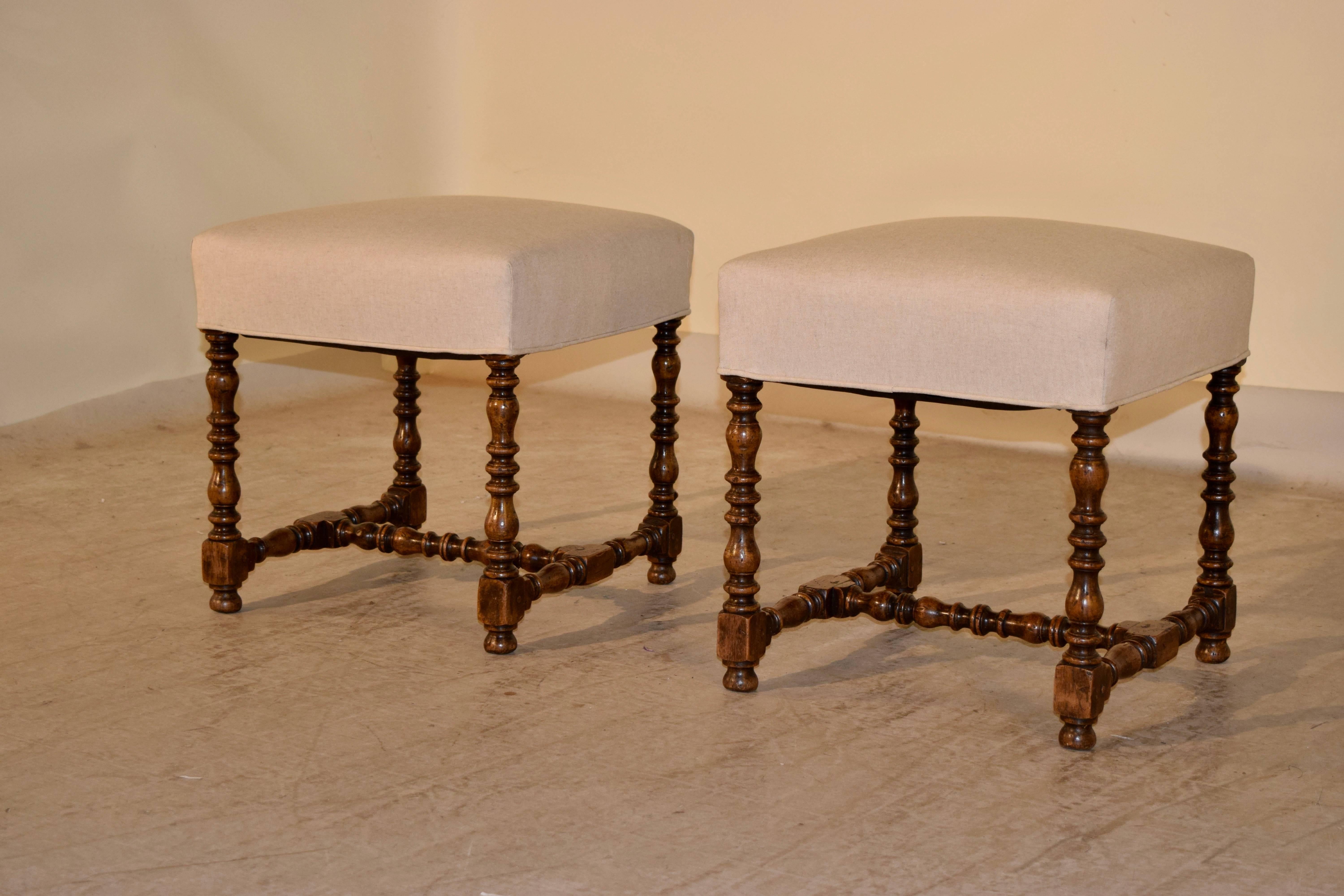 19th century pair of French stools made from walnut. The seats have been newly upholstered in linen and finished with a single welt. The legs and cross stretcher are hand-turned.