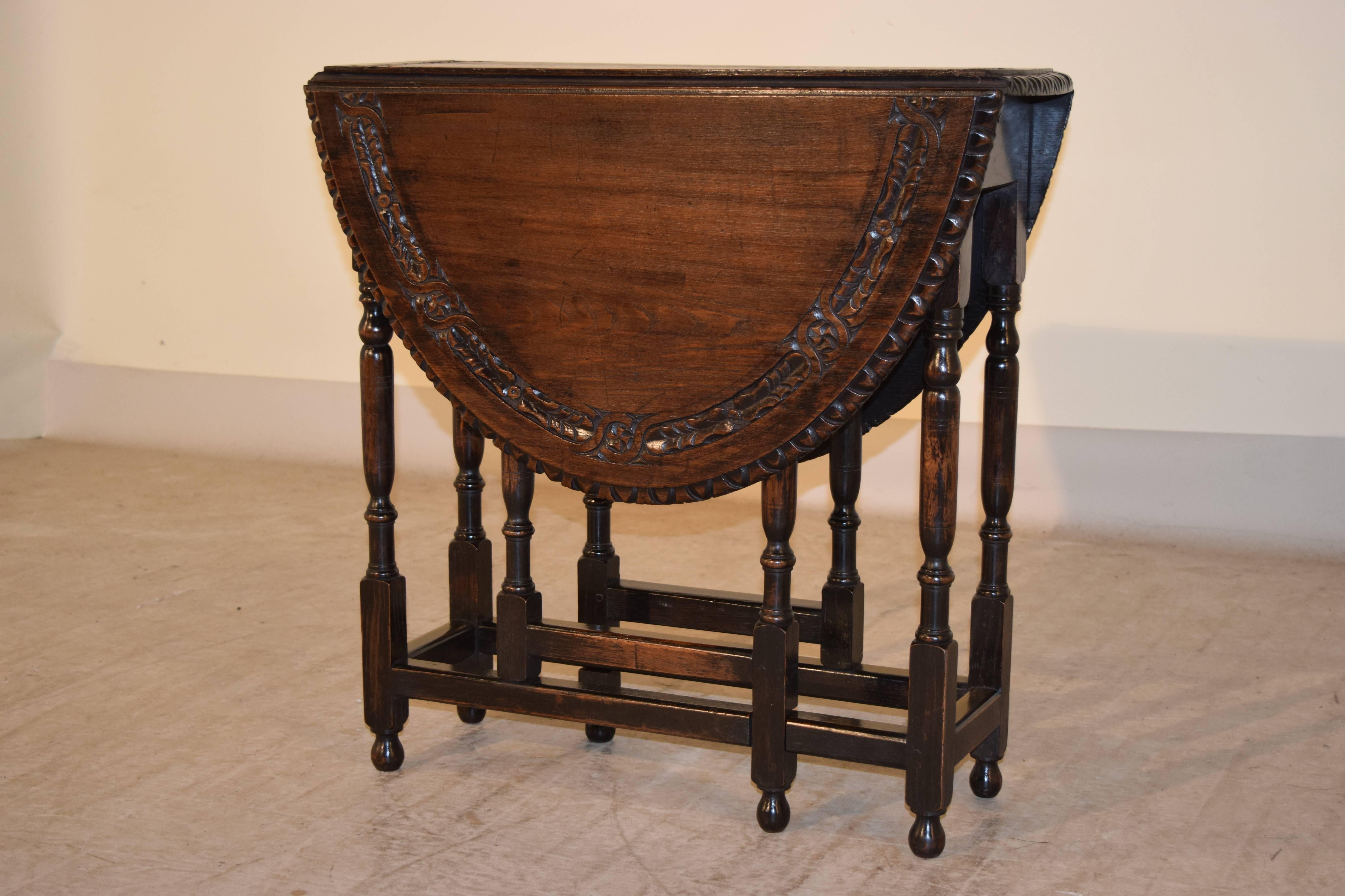 19th century carved oak gateleg table from England. The top has a beveled and carved decorated edge and a band of carving around the top, following down to a simple apron and hand-turned legs and stretchers. Raised on turned feet. The top open