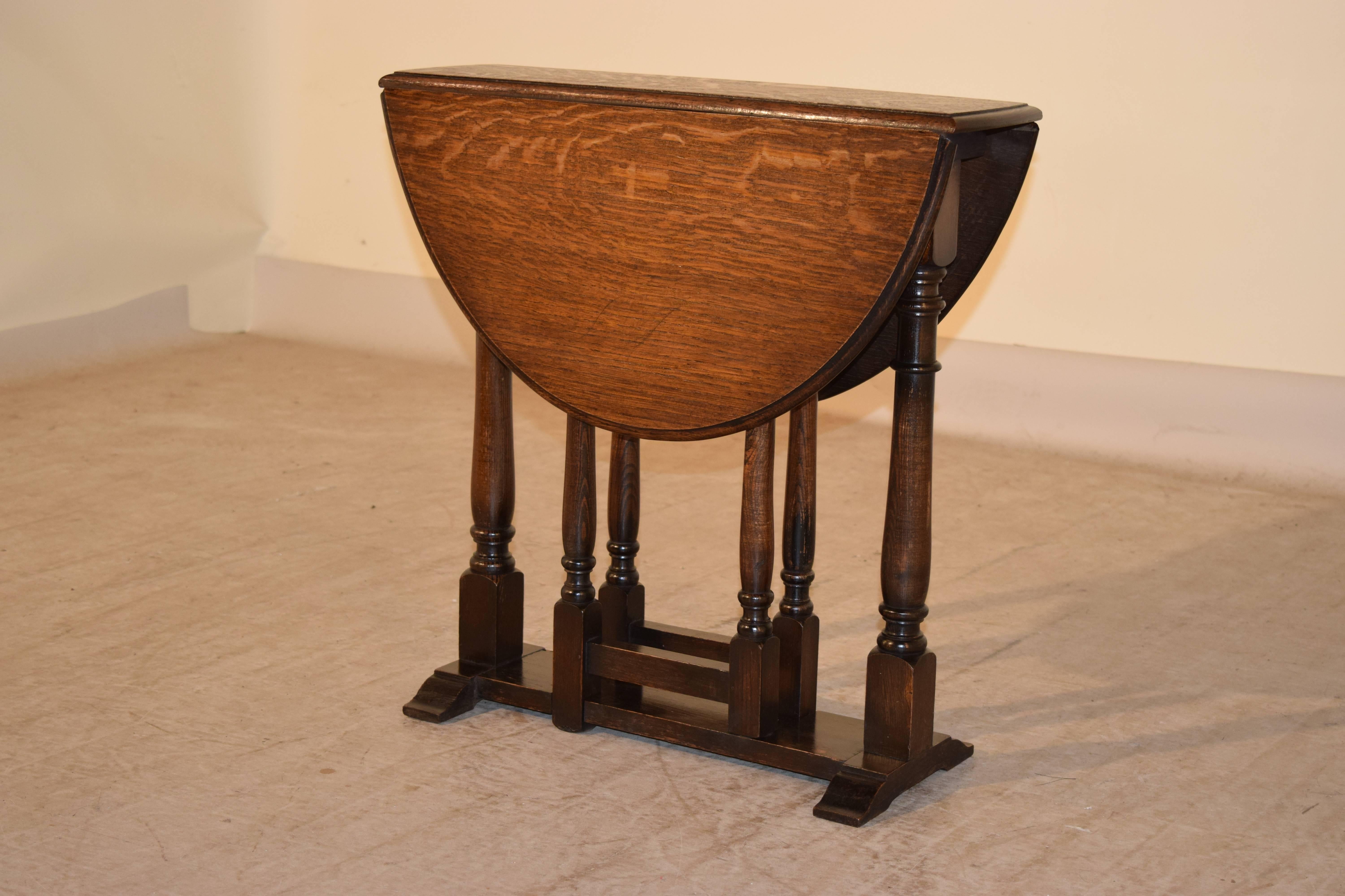 English oak gateleg table with a beveled edge around the top, following down to a simple apron and a trestle base with simple hand-turned legs, circa 1900. The top open measures 29.5