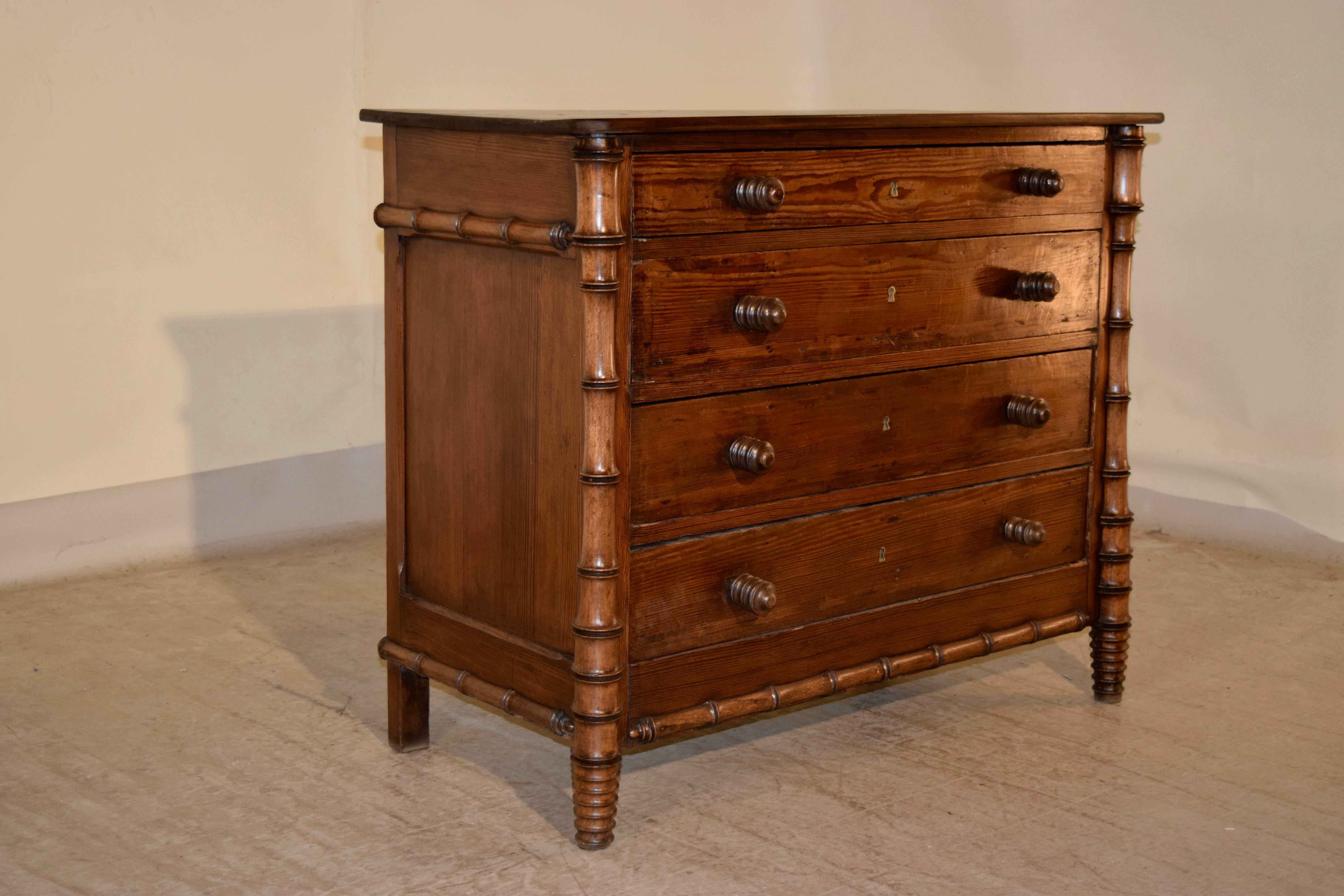 19th century chest of drawers from France with a pine top, following down to four drawers in the front and paneled sides which are banded with faux bamboo molding and corner columns. The drawer knobs are hand-turned in the same pattern to match.