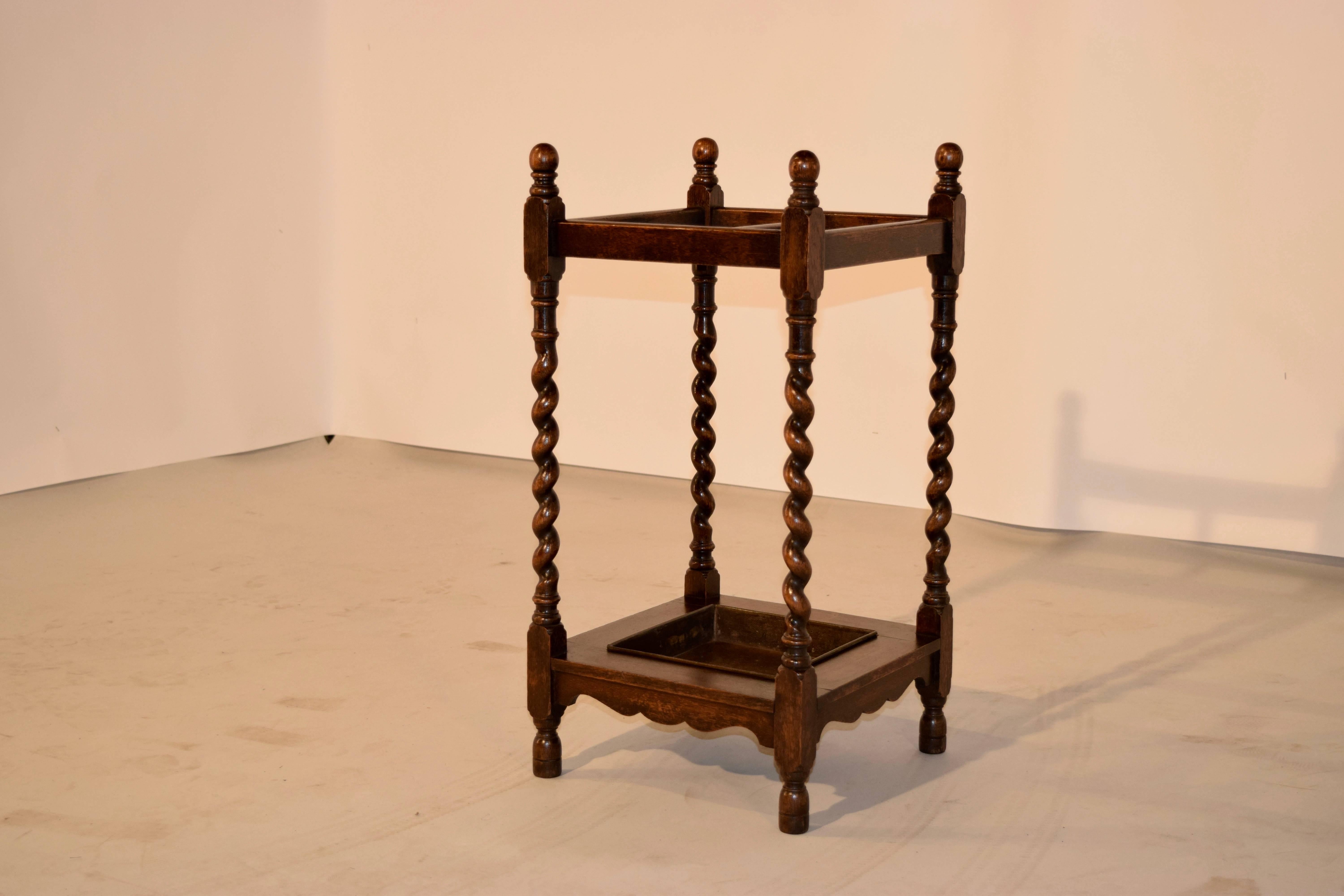 Late 19th Century English oak umbrella stand with hand-turned finials on the top, following down to hand-turned barley twist legs and turned feet. The legs are joined together by simple stretchers which are scalloped at the bottom, and have a