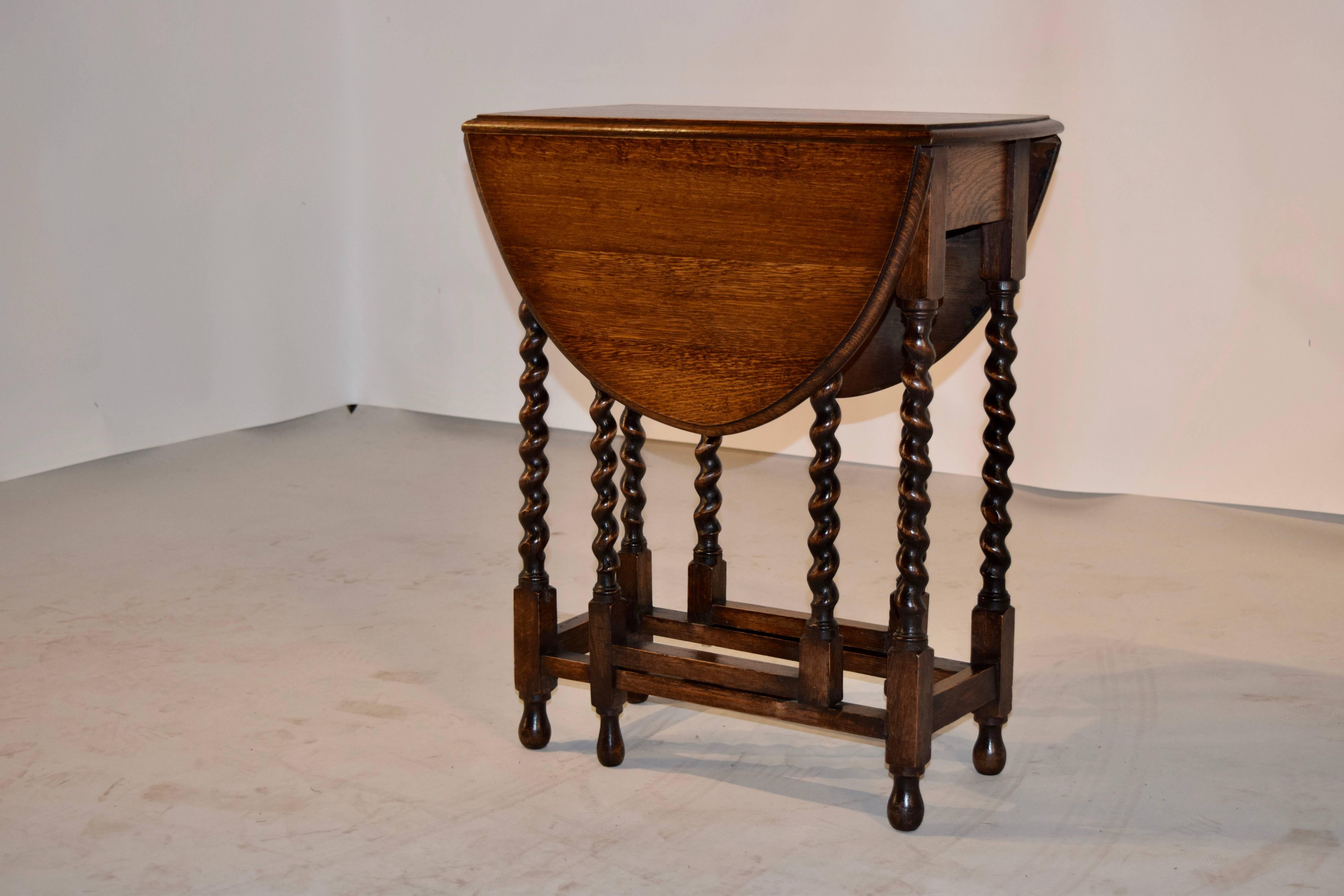 English oak gateleg table with a beveled edge around the top following down to a simple apron and hand-turned barley twist legs, joined by simple stretchers and raised on turned feet, circa 1900. The top open measures 36.25 x 23.