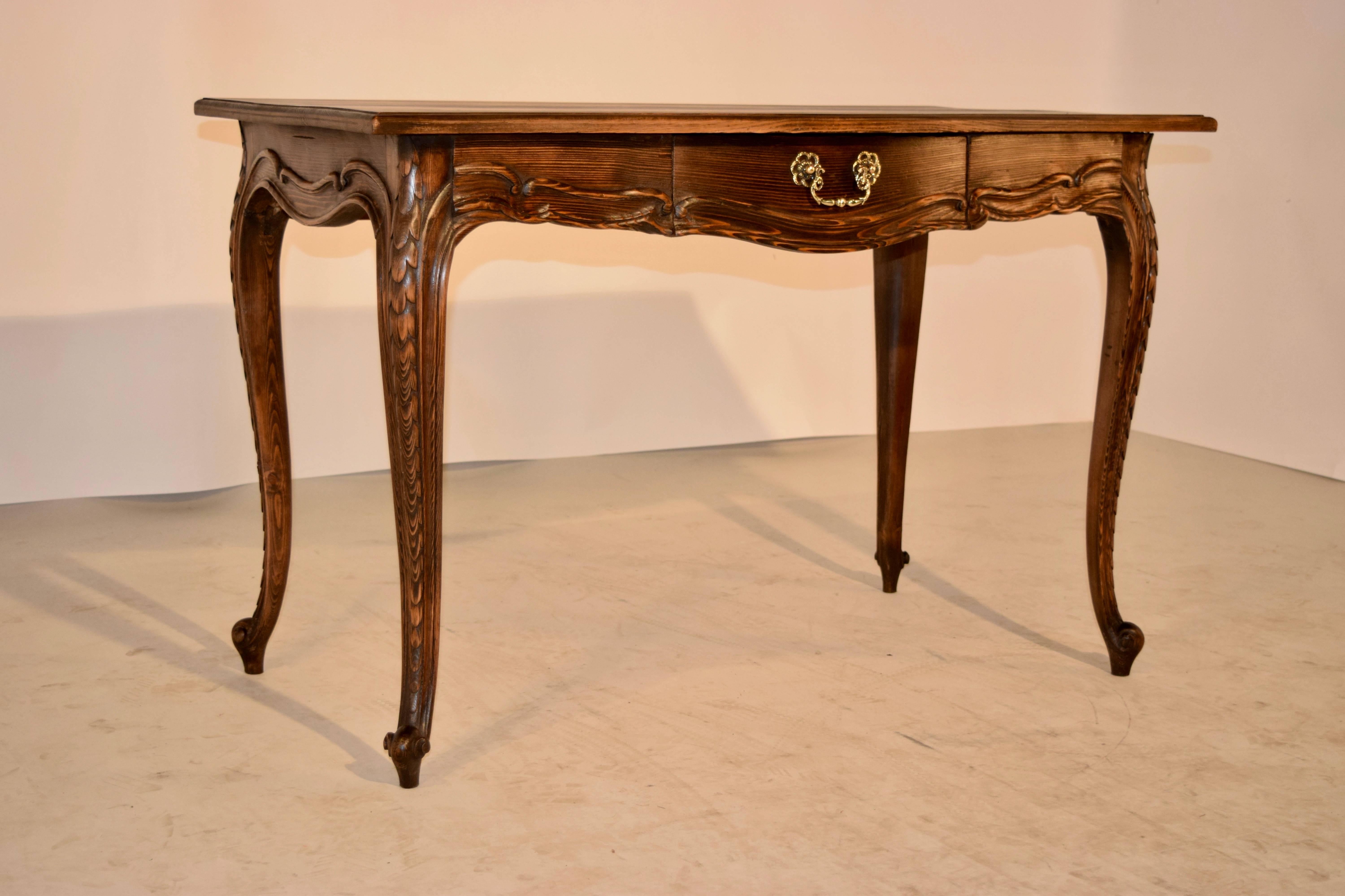19th century French pine side table with a shaped top which has a bevelled edge, following down to a scalloped apron, which has a carved border and a single drawer in the front. The legs are cabriole and are hand-carved decorated down the sides,