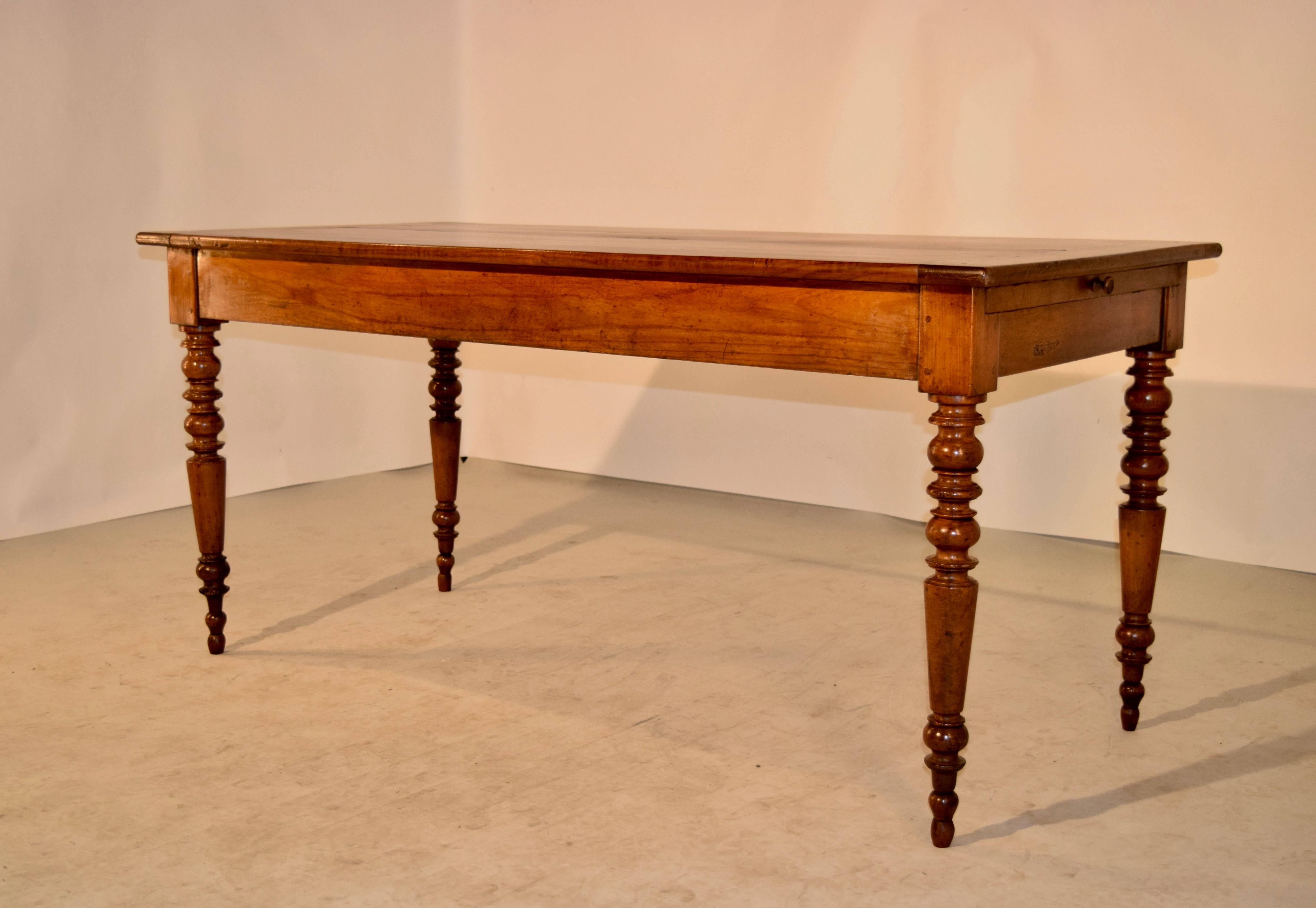 19th century French farm table made from cherry. The top is made up of thick cherry planks, and has banded ends, following down to a simple apron, which contains a drawer at one end and an extending bread board on the opposite end. The table is