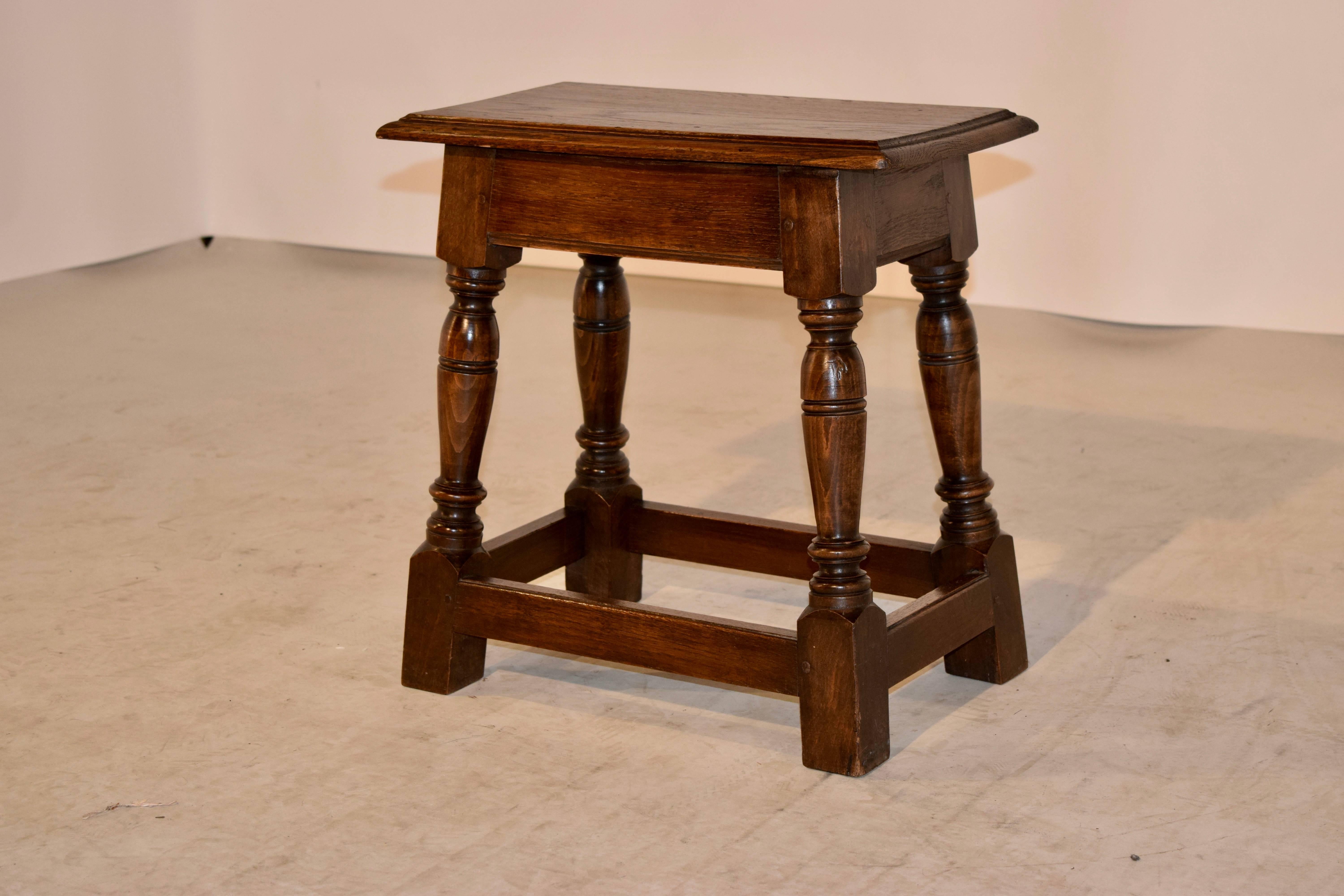 19th century English oak joint stool with a molded and beveled edge around the top, following down to a simple apron and hand-turned splayed legs, joined by simple stretchers.