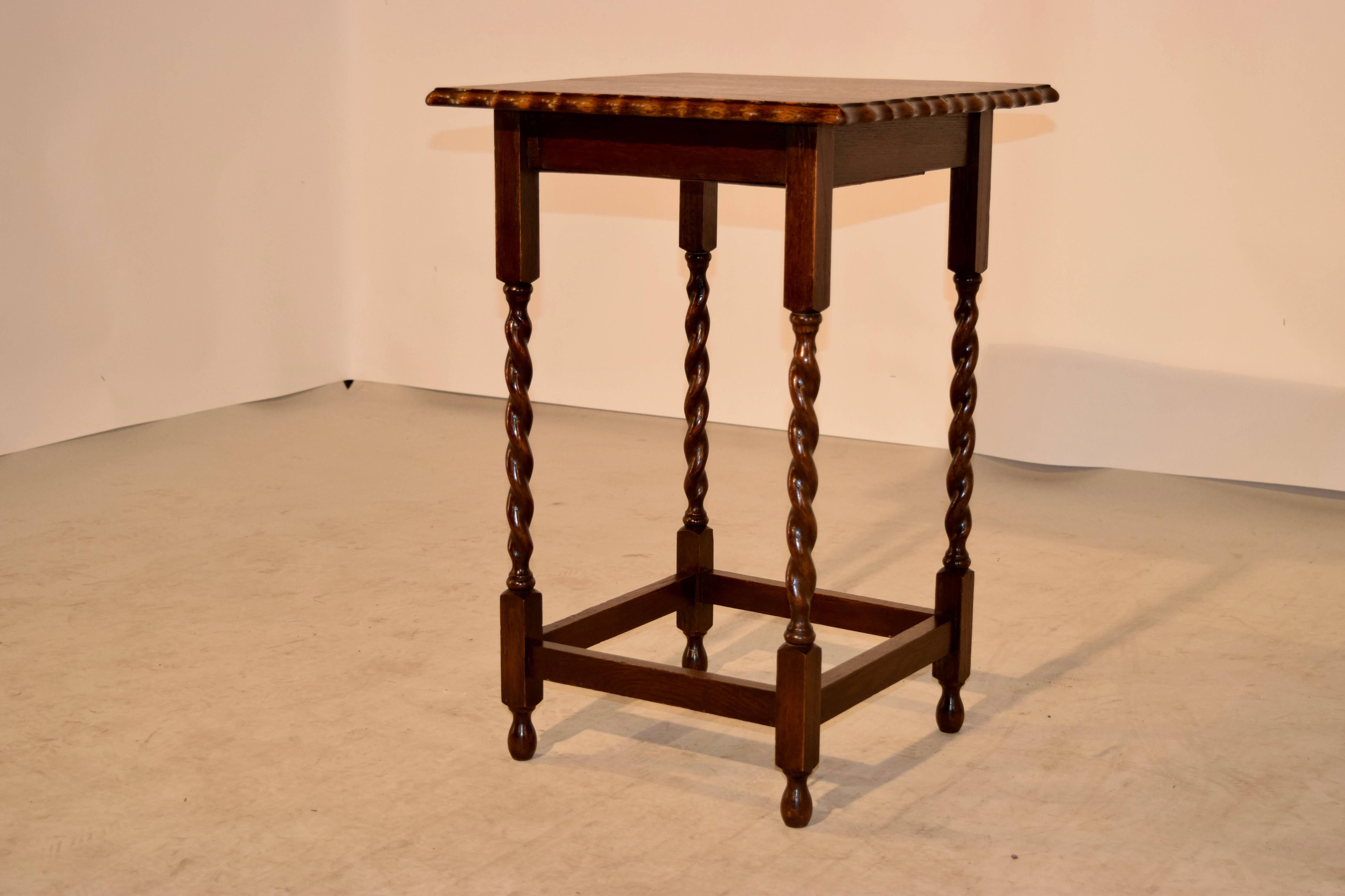 English side table with a square top, which has a scalloped and beveled edge following down to a simple apron and hand-turned barley twist legs, joined by stretchers and raised on turned feet.