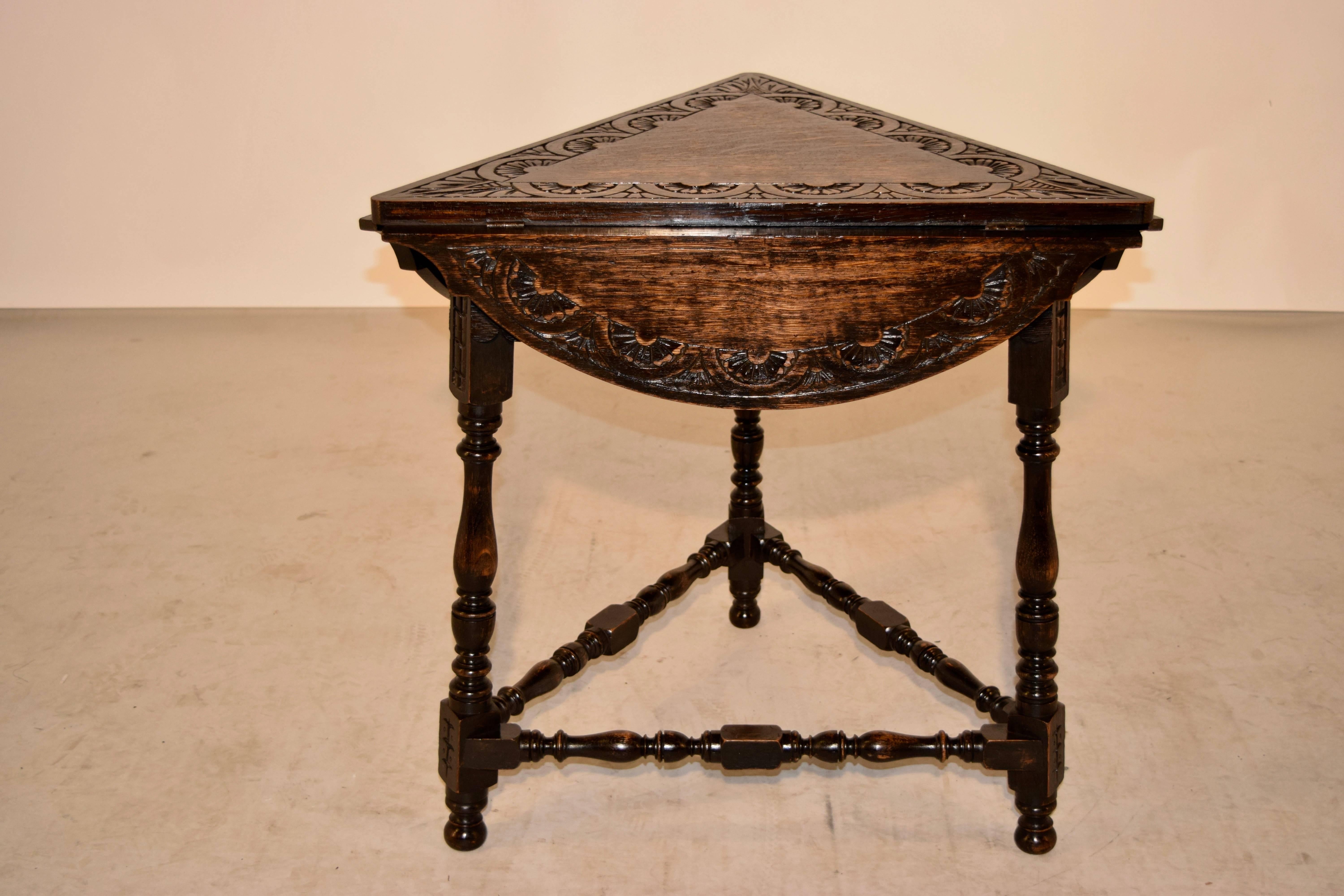 19th century English oak handkerchief table with three carved and scalloped drop leaves and a carved banded center, following down to a hand scalloped apron and supported on hand-turned legs and stretchers. Table open measures 28.63 x 29.