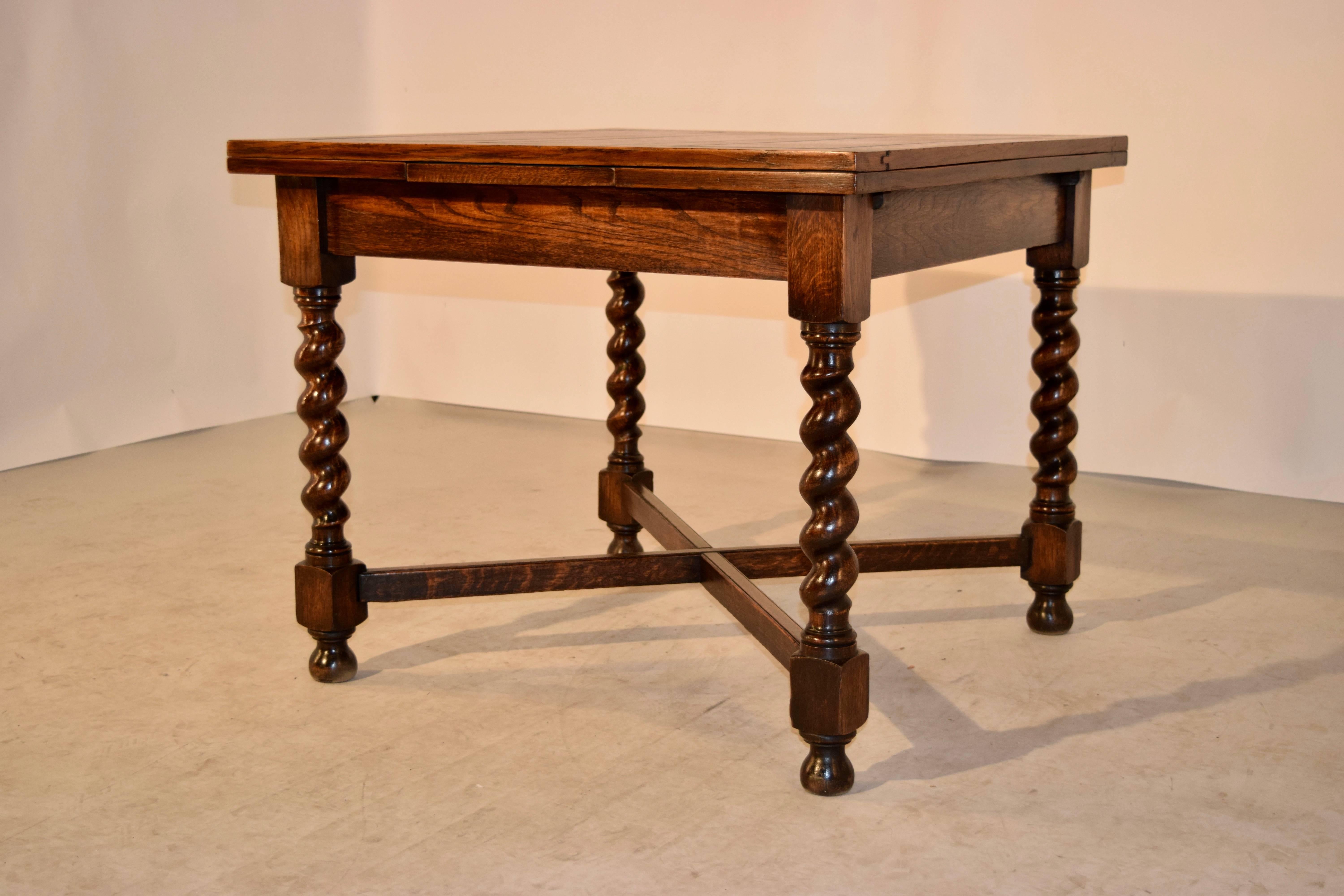 English oak draw-leaf table from England, circa 1900. The top and leaves are paneled and follow down to a simple apron, supported on thickly turned barley twist legs, joined by cross stretchers and raised on turned feet. The top open measures 59.75
