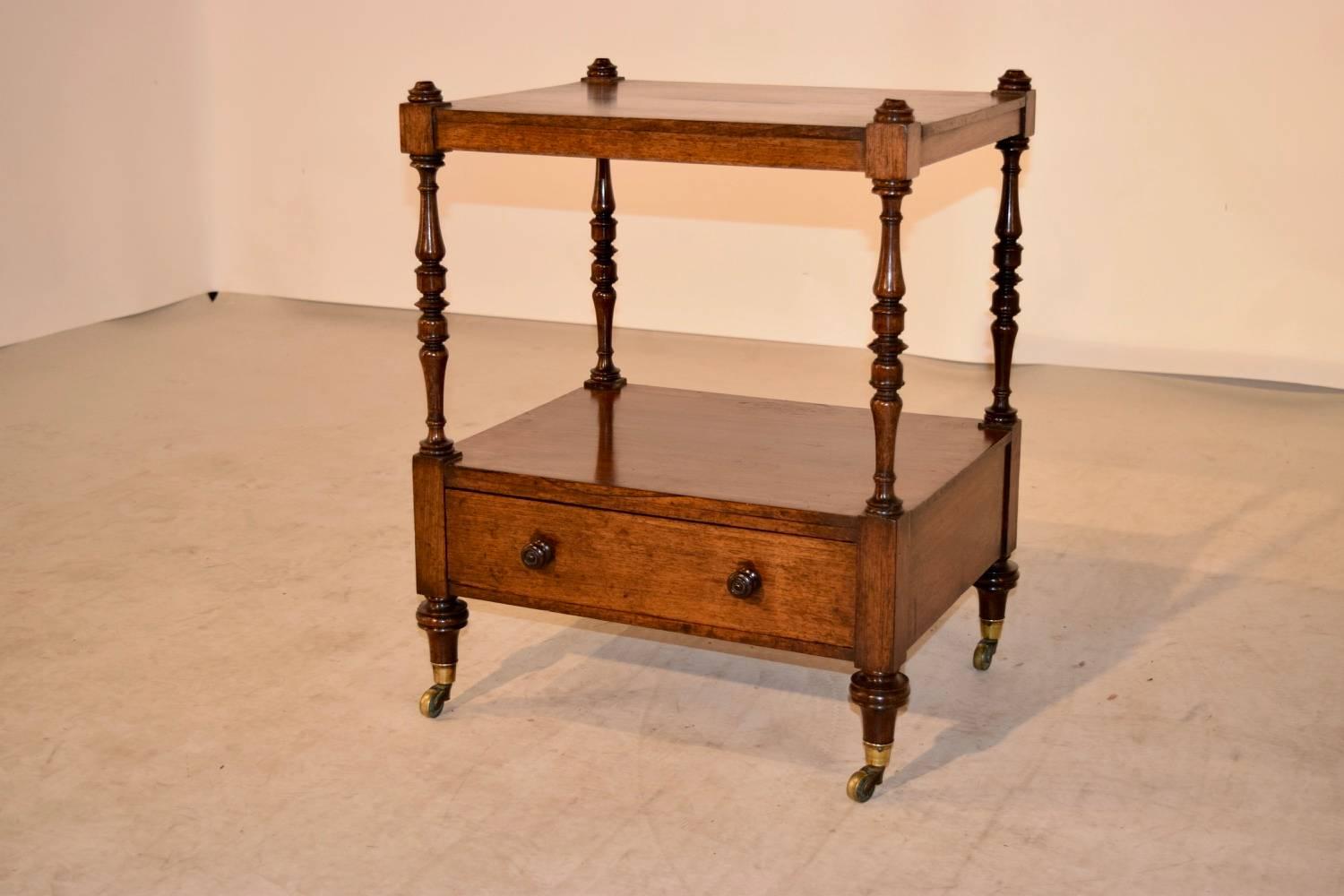 19th century English small shelf made from rosewood. There are hand-turned finials on the top which follow down to two shelves, the bottom shelf with a drawer. The piece has wonderfully hand-turned shelf supports and feet, supported on brass castors.