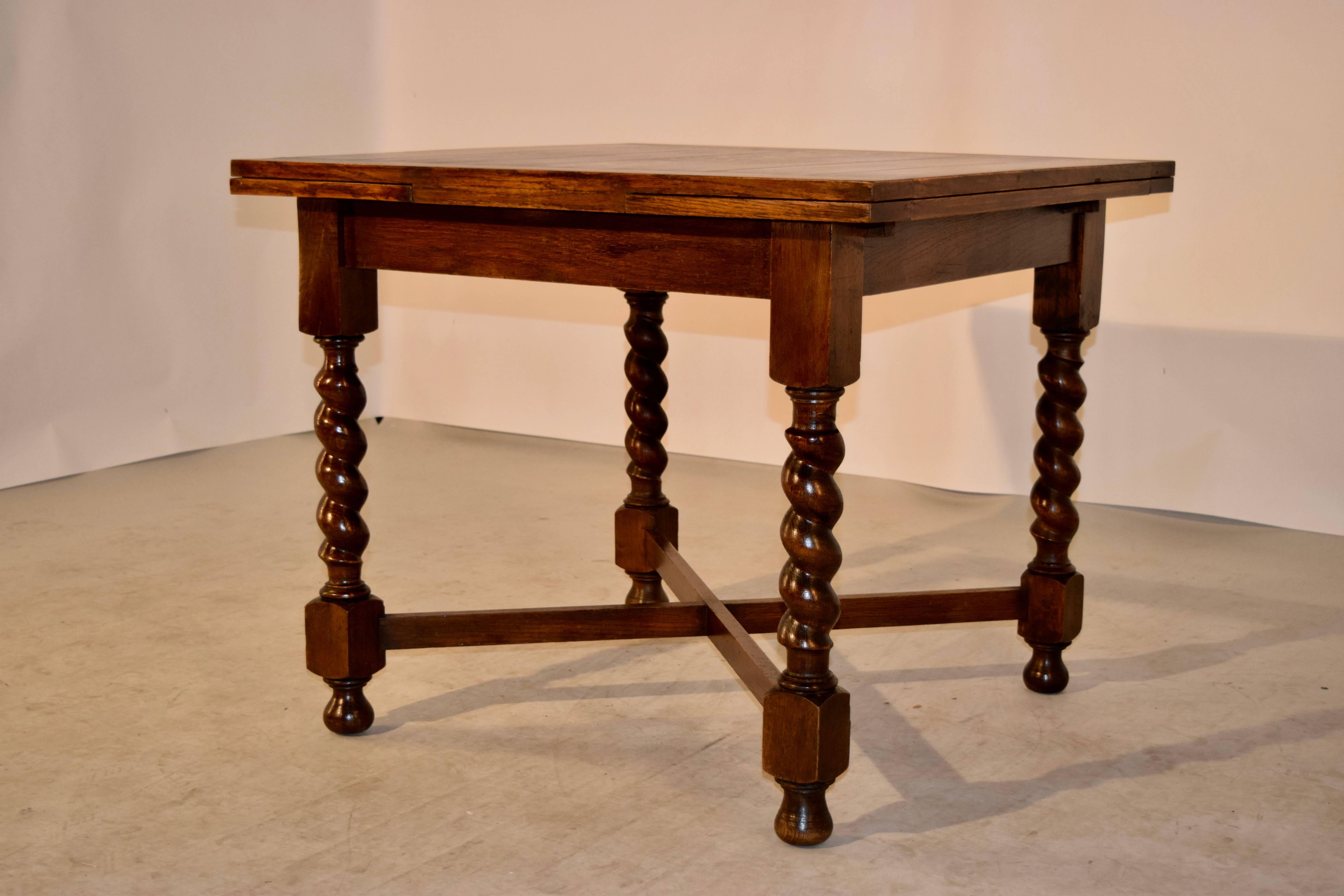 English oak table with draw-leaves, circa 1900. The top and leaves are paneled and follow down to a simple apron and four hand-turned barley twist legs, one of which is slightly slanted, as seen in the photos. The legs are joined by cross