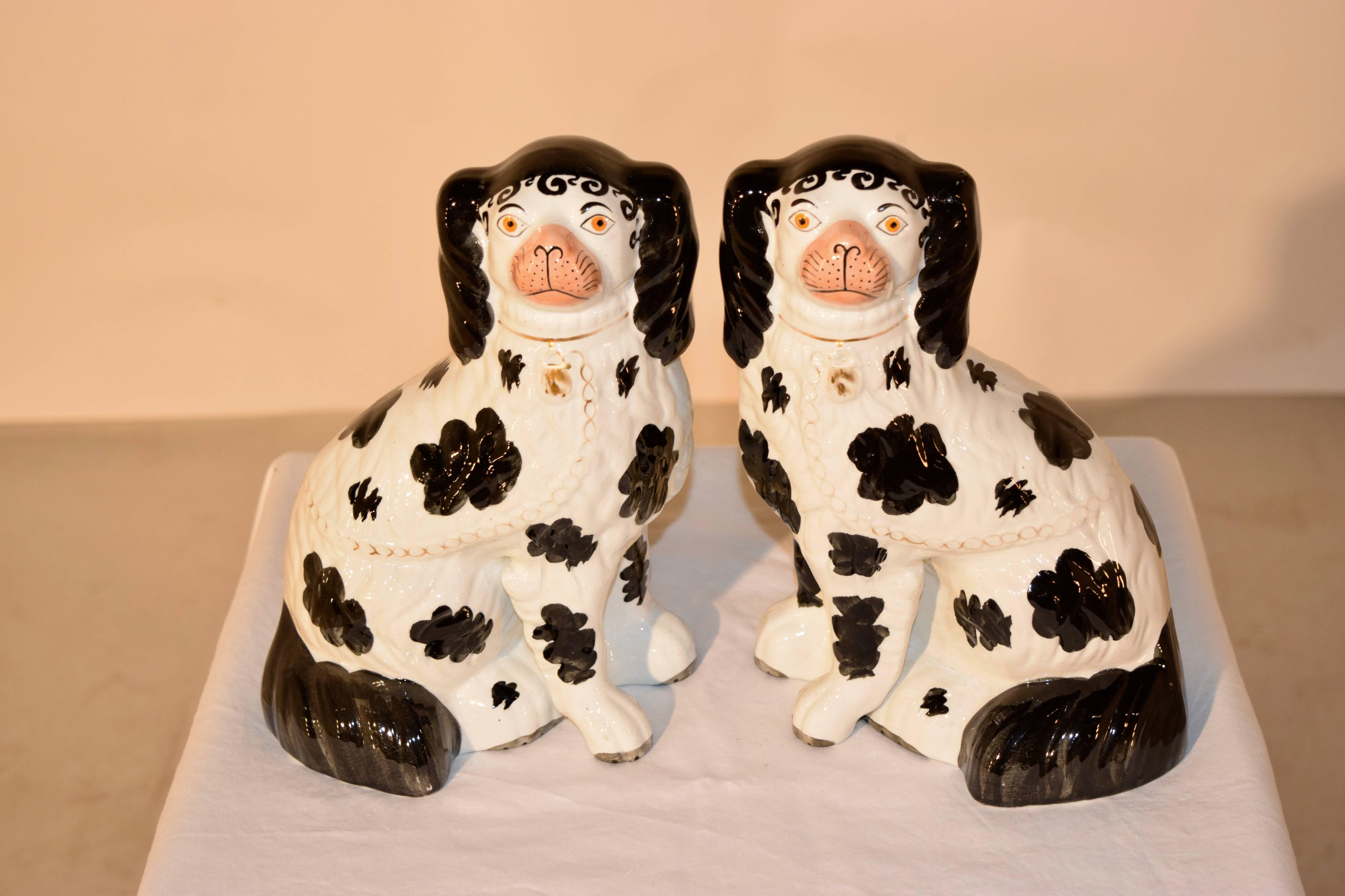 19th Century pair of Staffordshire spaniels in the Disraeli style. The spaniels have separated front legs, and are painted in a black and white design. The design is named after Benjamin Disraeli, who was the Prime Minister to England twice during