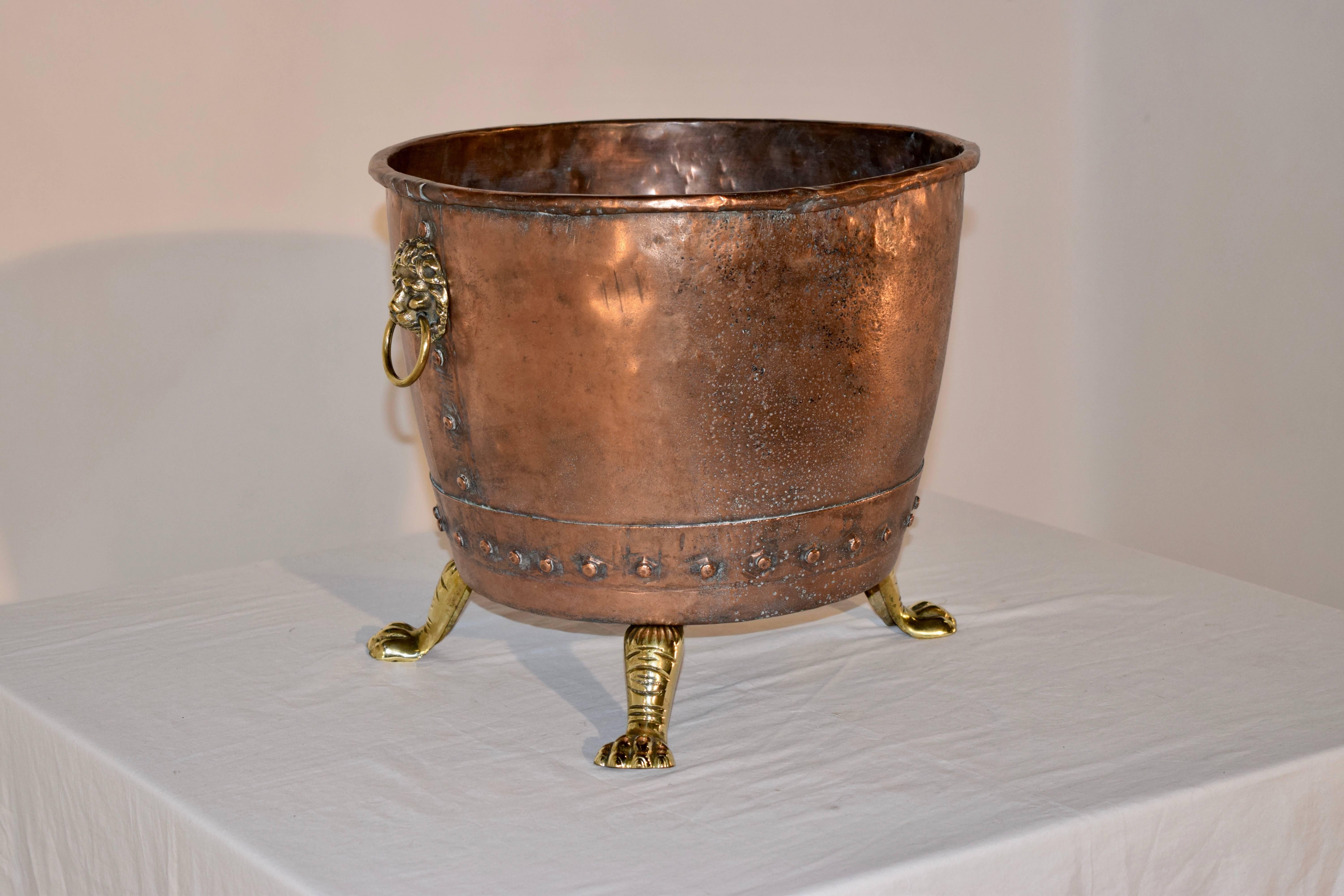 19th century hammered copper log bucket from England. The top has a rolled edge and has gorgeous riveting detail on the seams. The handles are hand cast brass lions with rings, and the piece is raised on hand cast brass feet.