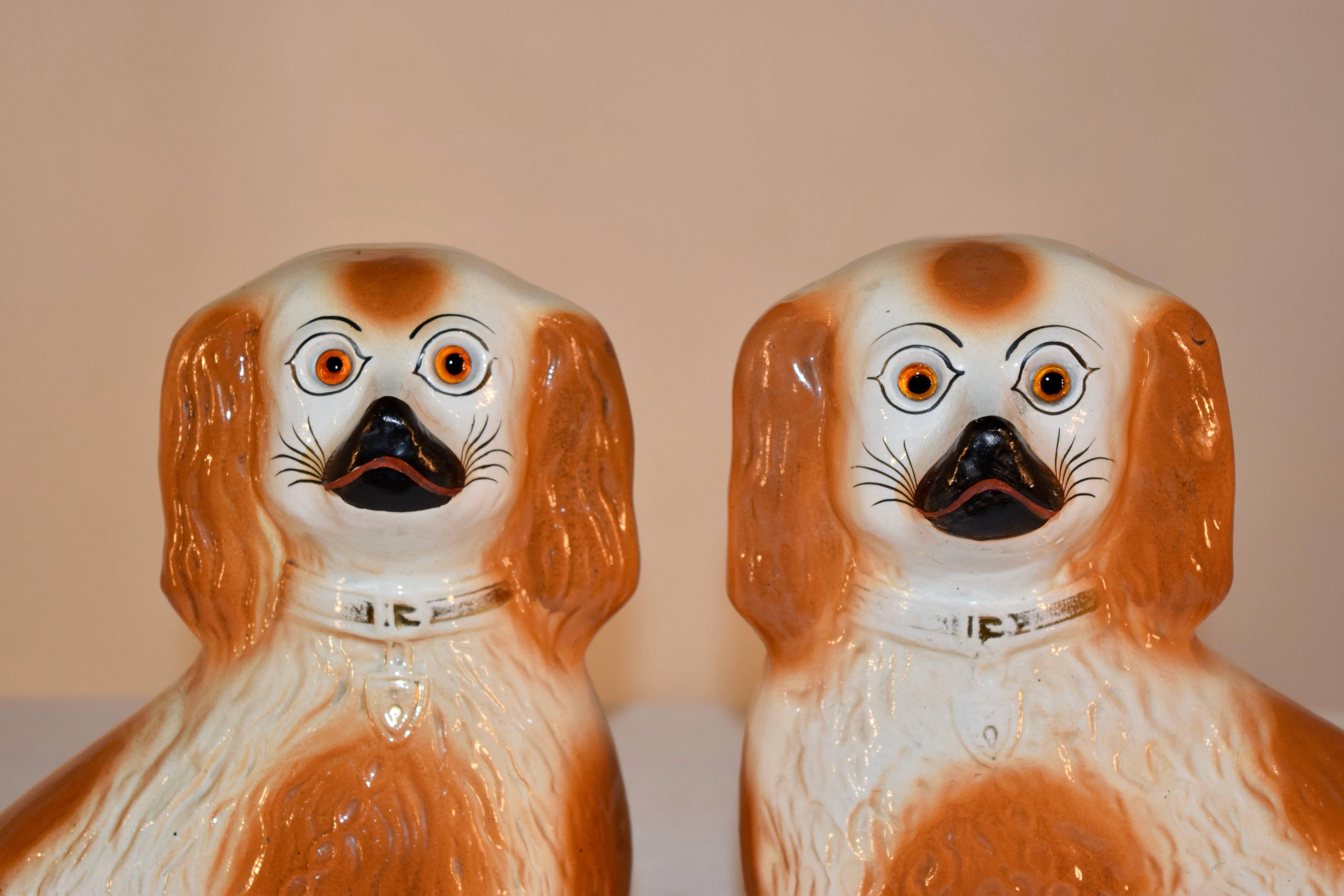 paire de jolis chiens en porcelaine du 19e siècle provenant de la région du Staffordshire en Angleterre. Ils ont des queues bouclées et des yeux de verre, et sont décorés d'une couleur rouille.