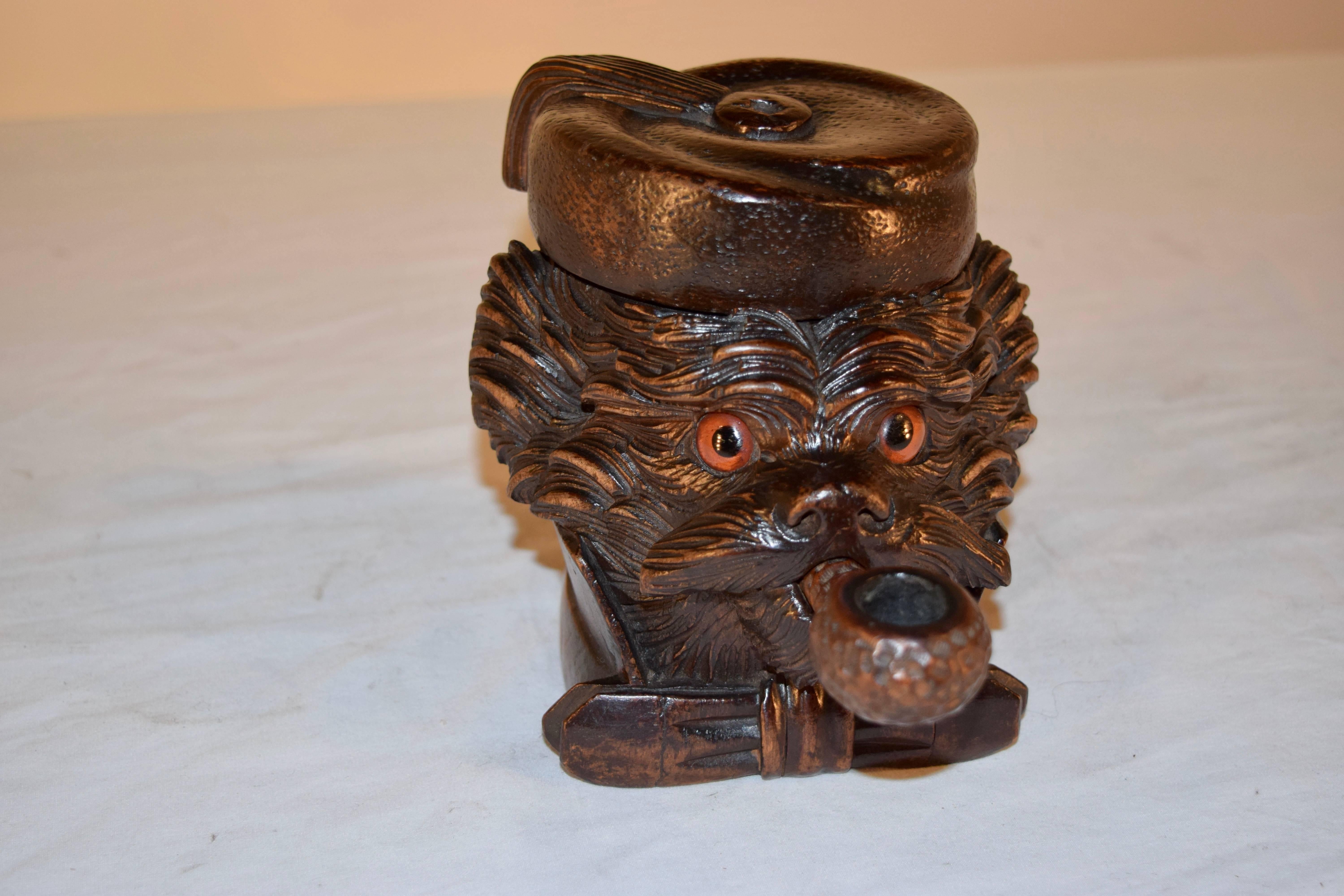 19th century hand-carved Black Forest dog's head humidor. The dog is wearing a hat, which lifts to reveal a storage compartment for pipe tobacco. The pipe is removable as well. The carving is lovely on this piece.