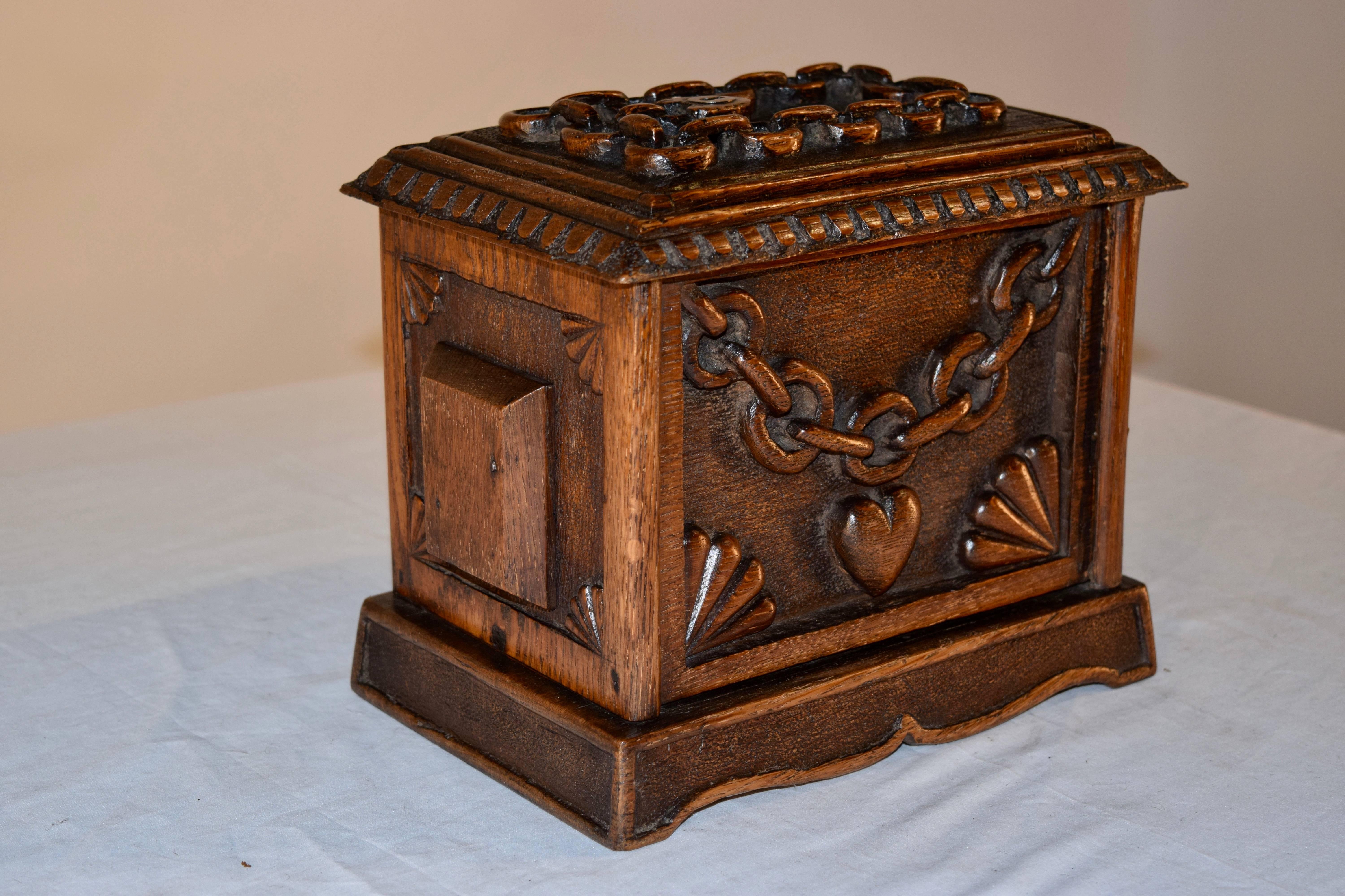19th century hand-carved Folk Art jewelry box with chain and heart design made from oak from England. It has an elaborately carved top and sides with a single drawer which opens from the side to reveal a storage compartment.