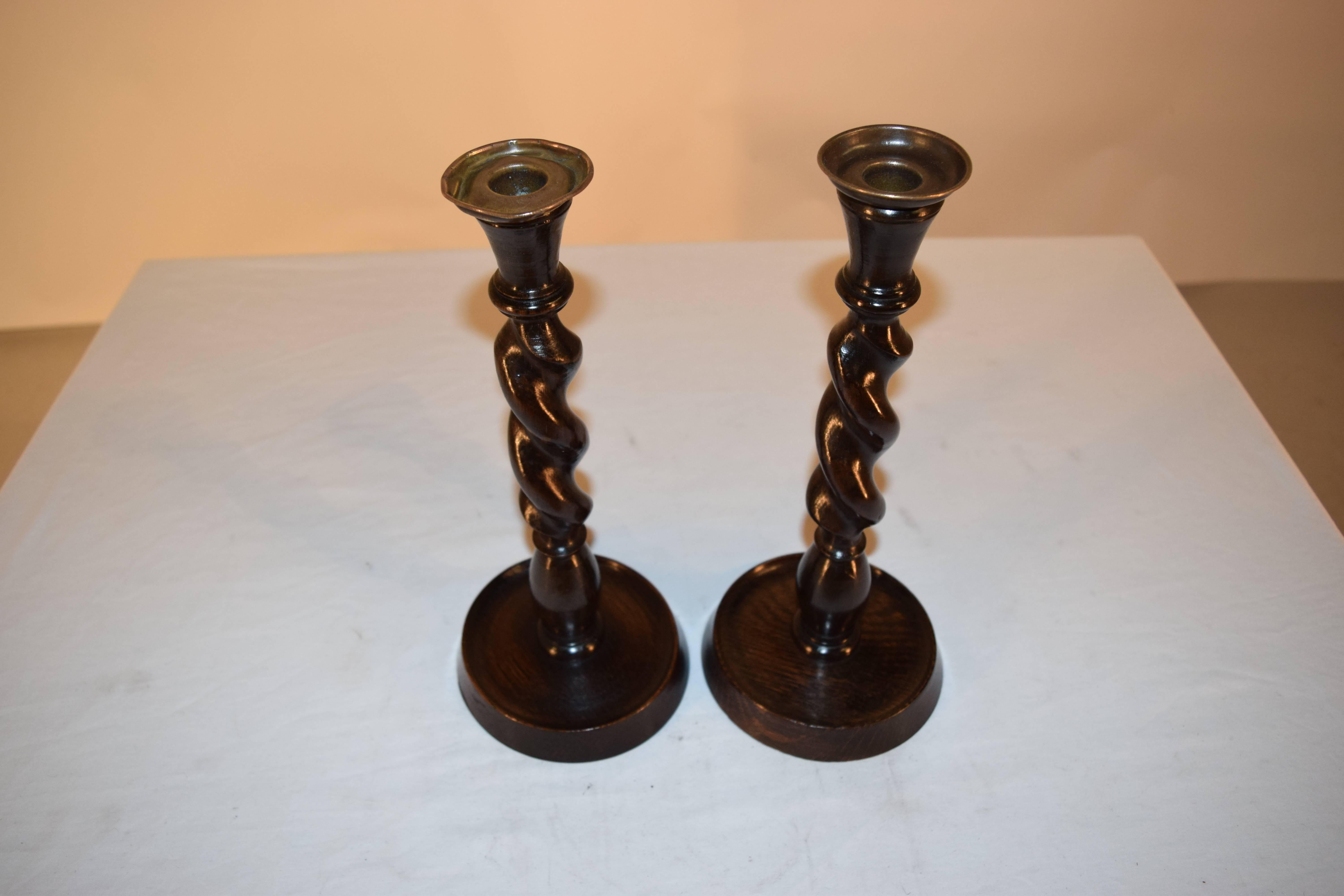 Pair of English oak hand-turned candlesticks with a cone shaped top, following down to barley twist stems, and shaped bases.