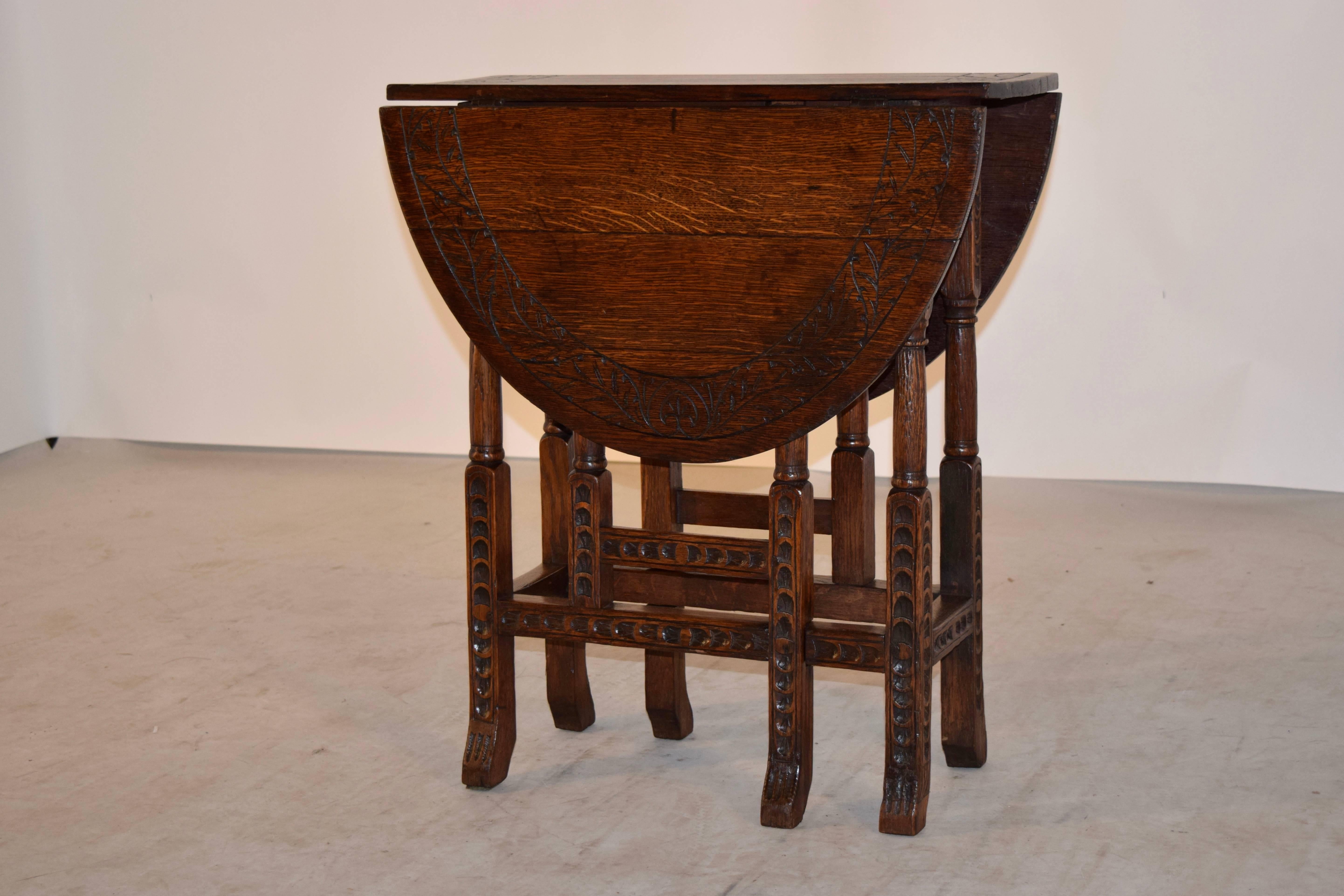 19th century English oak gate-leg table with a hand-carved border around the top, following down to hand carved and turned legs with splayed feet. The legs are joined by matching carved stretchers. The top open measures 35.75 x 24.25.