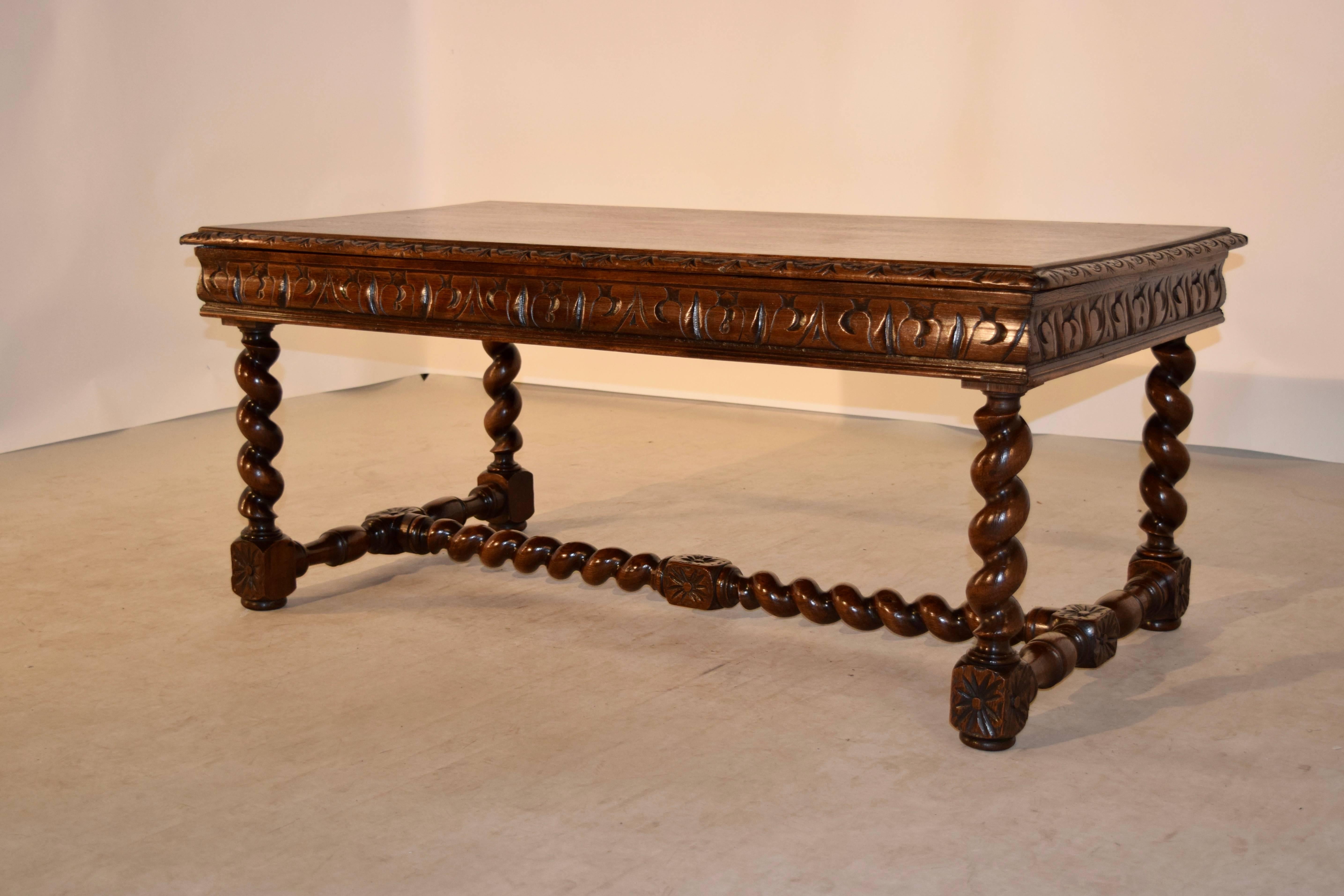 19th century oak coffee table from France. The top has a beveled and gadrooned edge around the top, following down to a hand-carved apron, which conceals a large single drawer in the front. The piece is raised on hand-turned barley twist legs, which