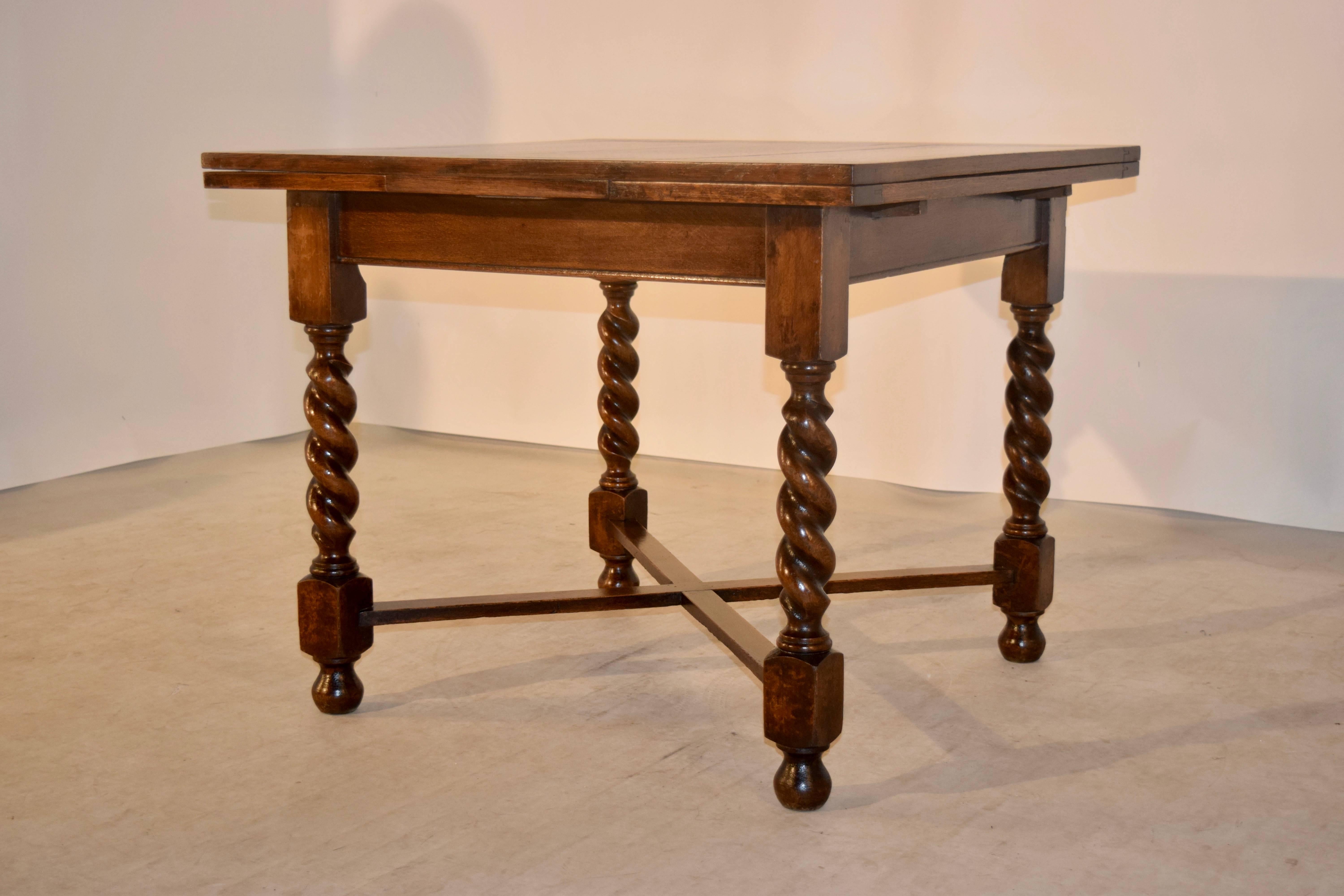 English oak draw-leaf table with paneled top and leaves, following down to a simple apron, and supported on hand turned barley twist legs, which are joined by cross stretchers and supported on turned feet, circa 1900. The top open measures 59.88 x