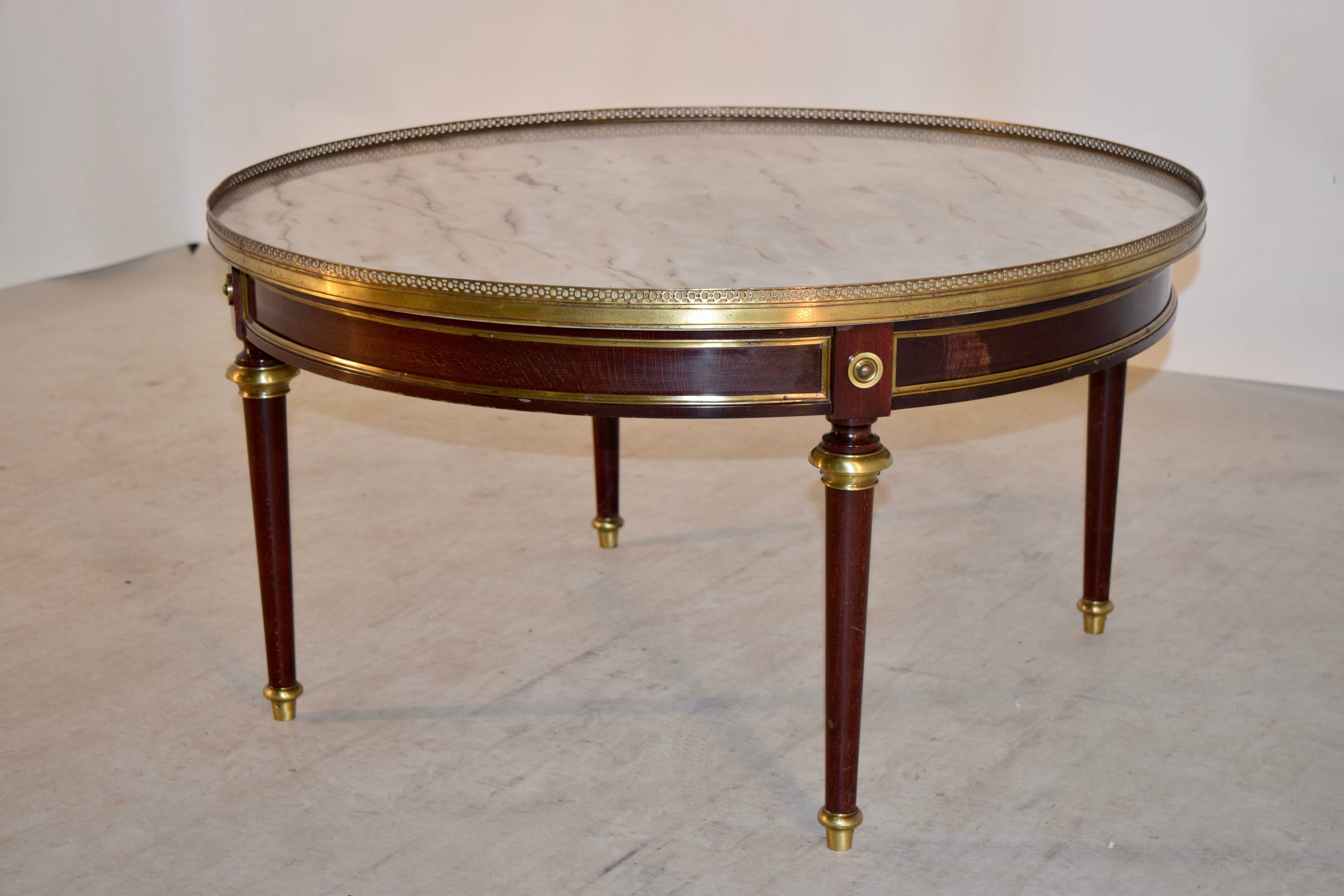 Regency style coffee table from England, circa 1920s. The top is marble, and is surrounded by a pierced brass gallery, following down to a round base made from Mahogany with brass molded decoration. The legs are shaped and end in brass caps.