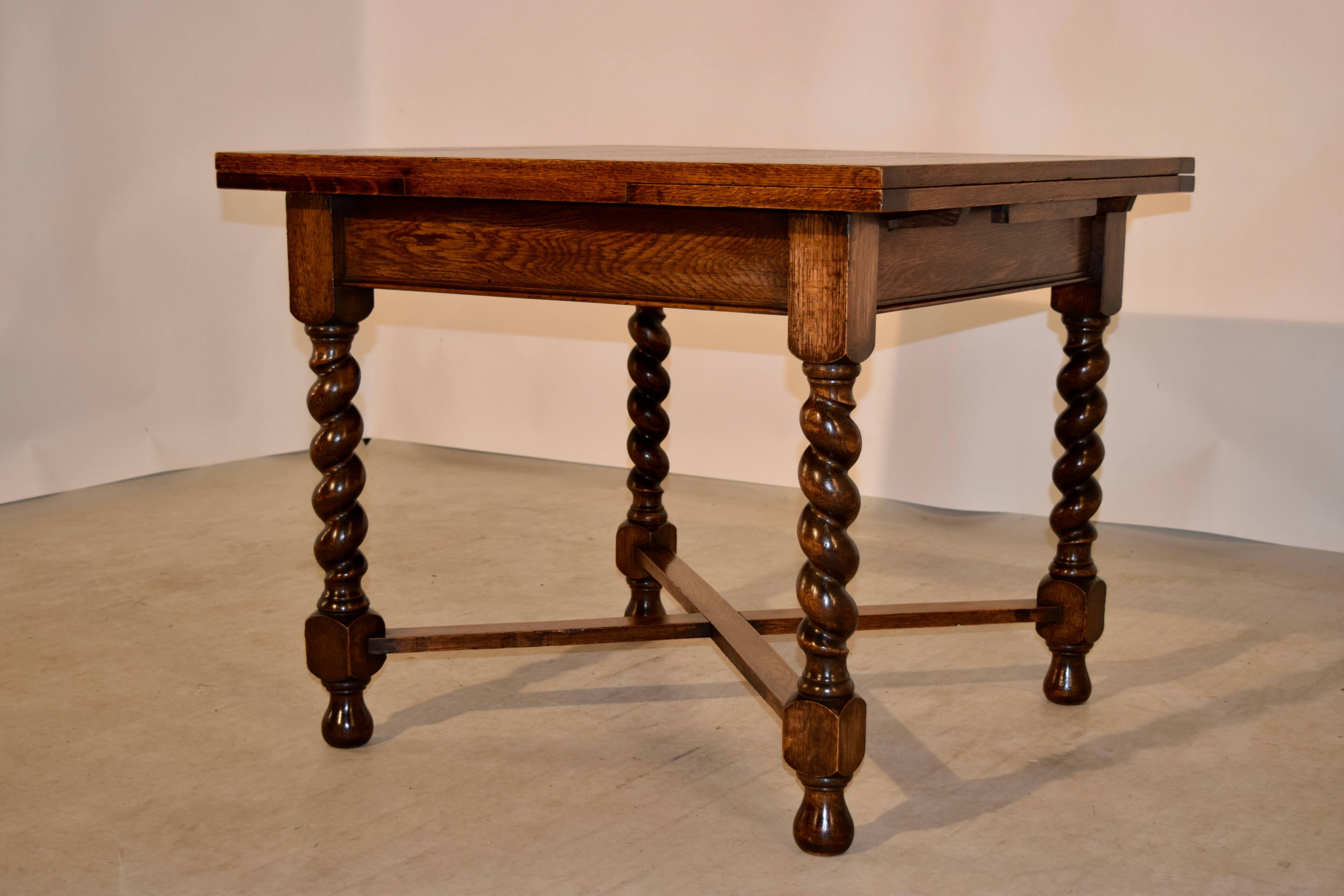 English oak draw-leaf table with paneled top and leaves, following down to a simple apron, and supported on hand-turned barley twist legs, which are joined by cross stretchers and supported on turned feet, circa 1900. The top open measures 60.13 x