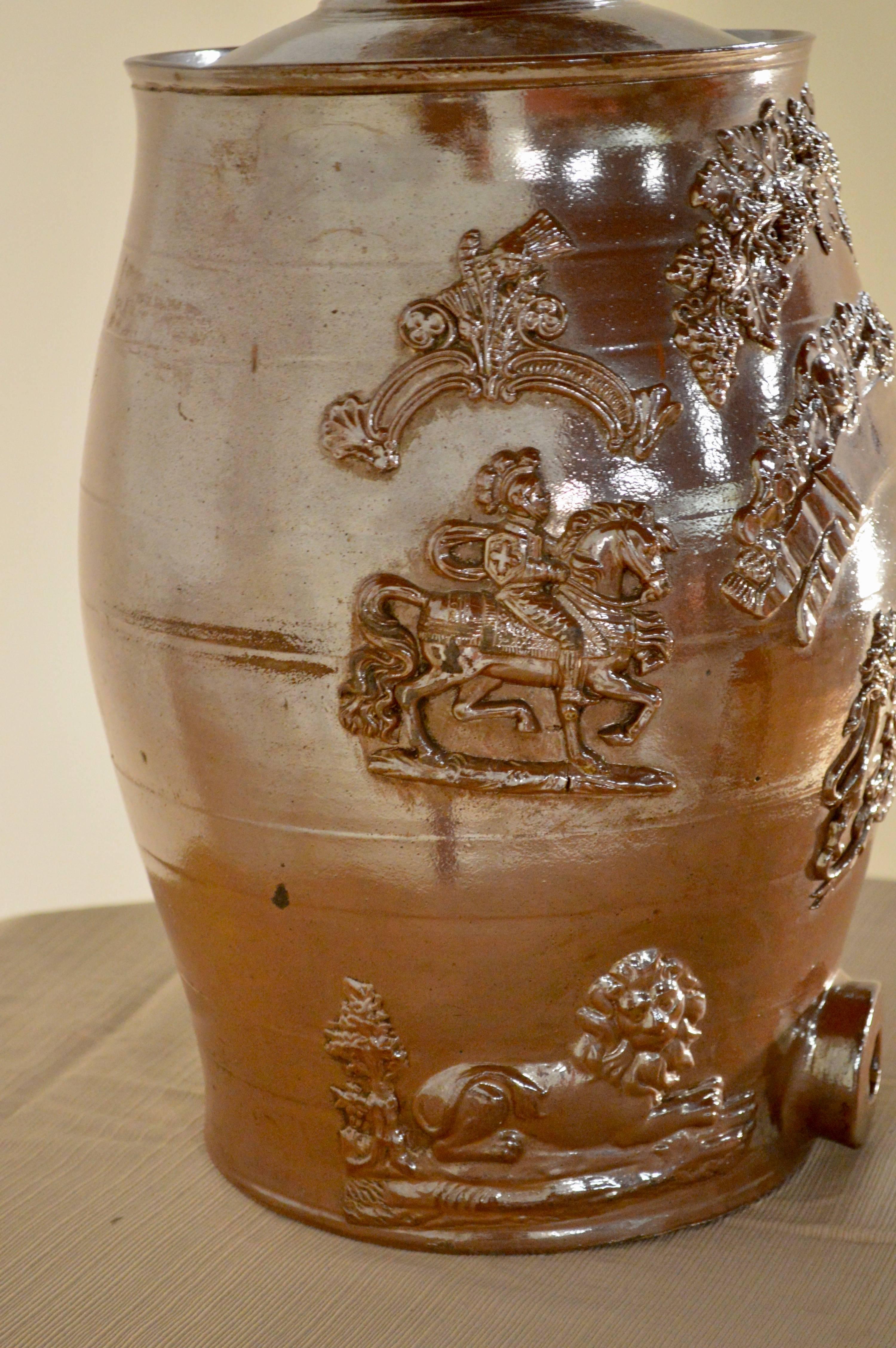 19th century English spirit barrel made of stoneware with alkaline glaze. Features relief designs on both sides of lions and knights on horses.
     