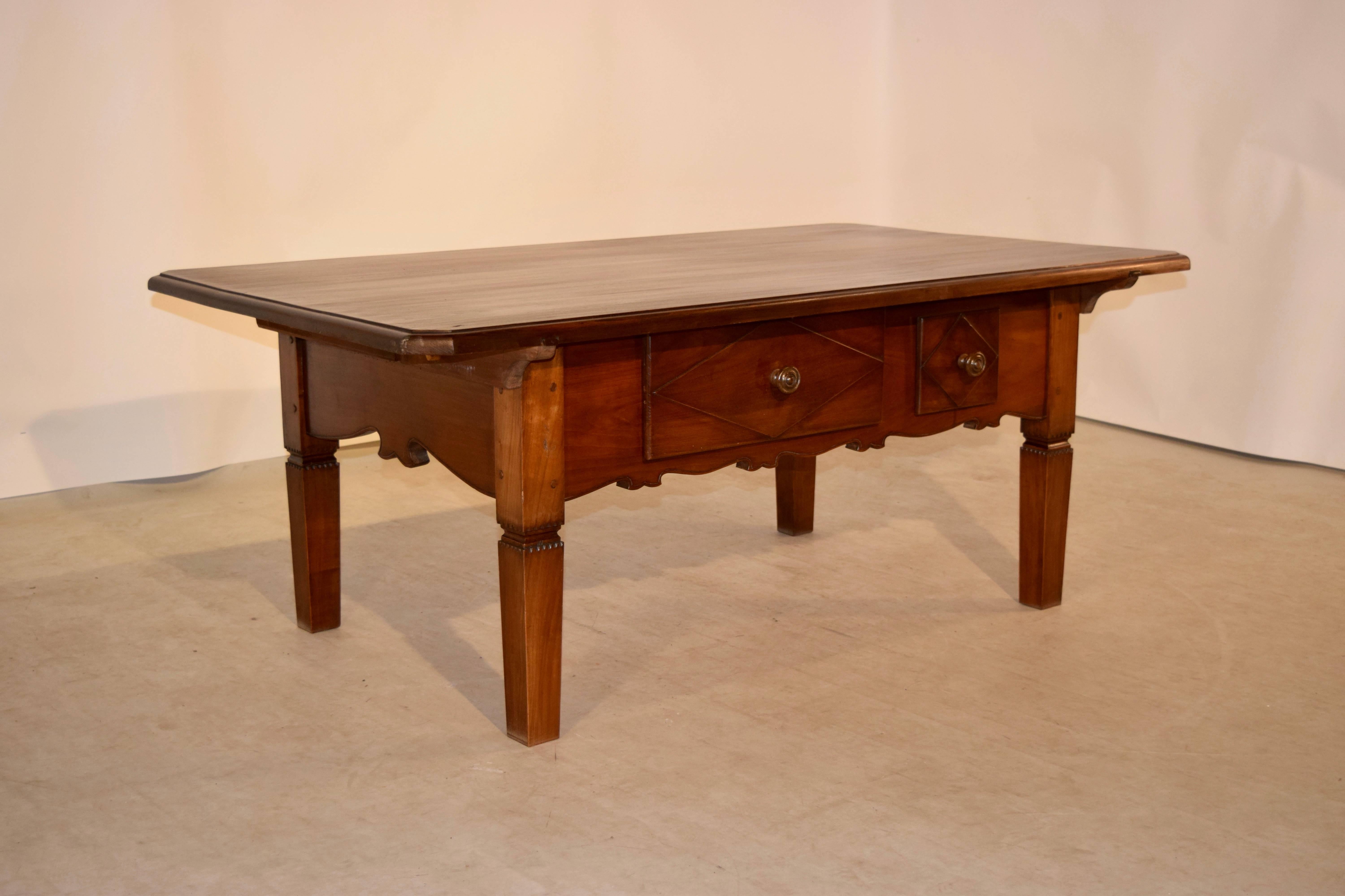 19th century Swiss coffee table made from cherry. The top is made from three boards with wonderful graining and a beveled edge with chamfered corners. The apron is scalloped and has two drawers in the front with geometric panel drawer fronts. The