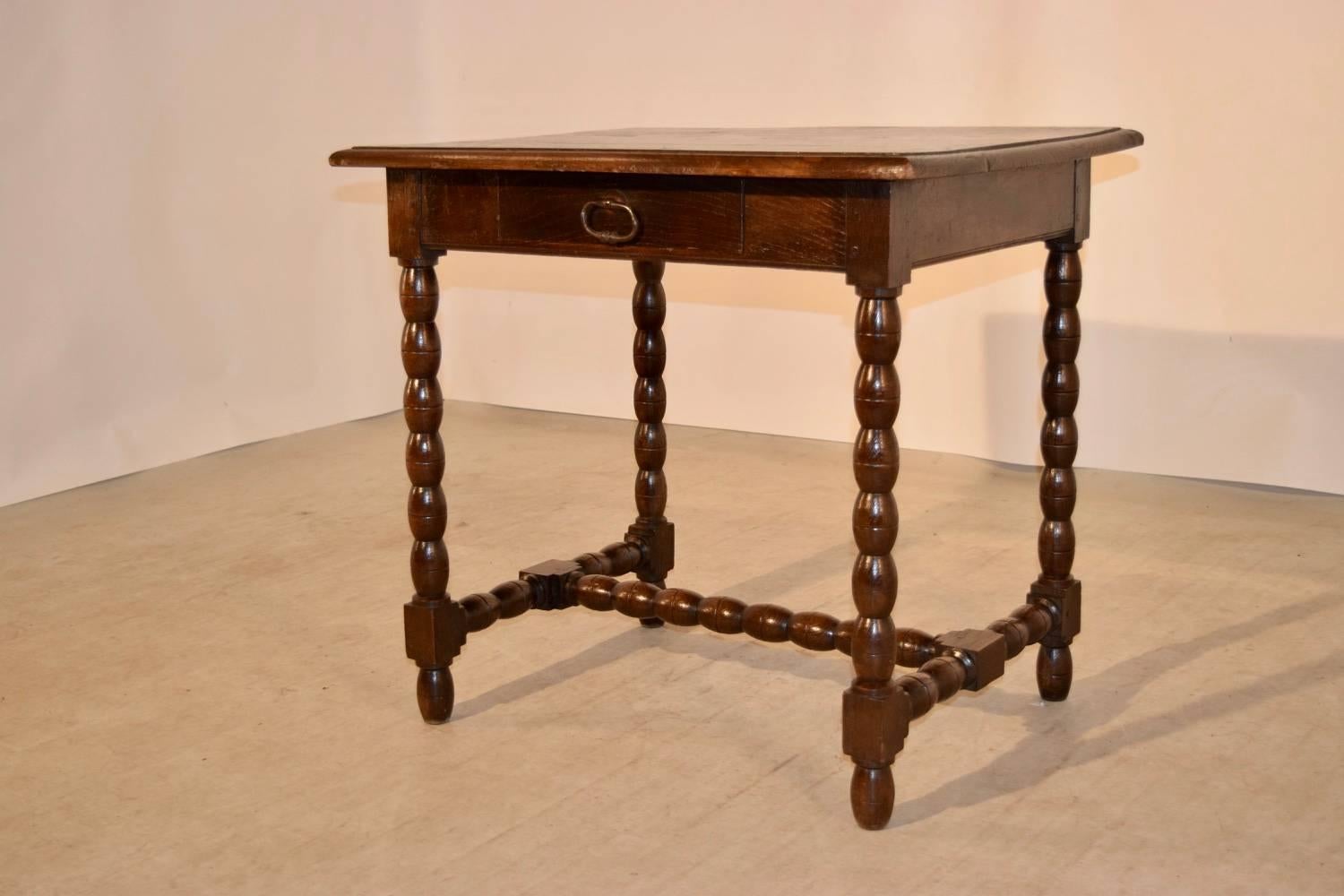 18th century English elm side table with a nicely beveled edge around top following down to a simple apron containing a single drawer and bobbin legs joined by matching stretchers. Raised on turned feet.