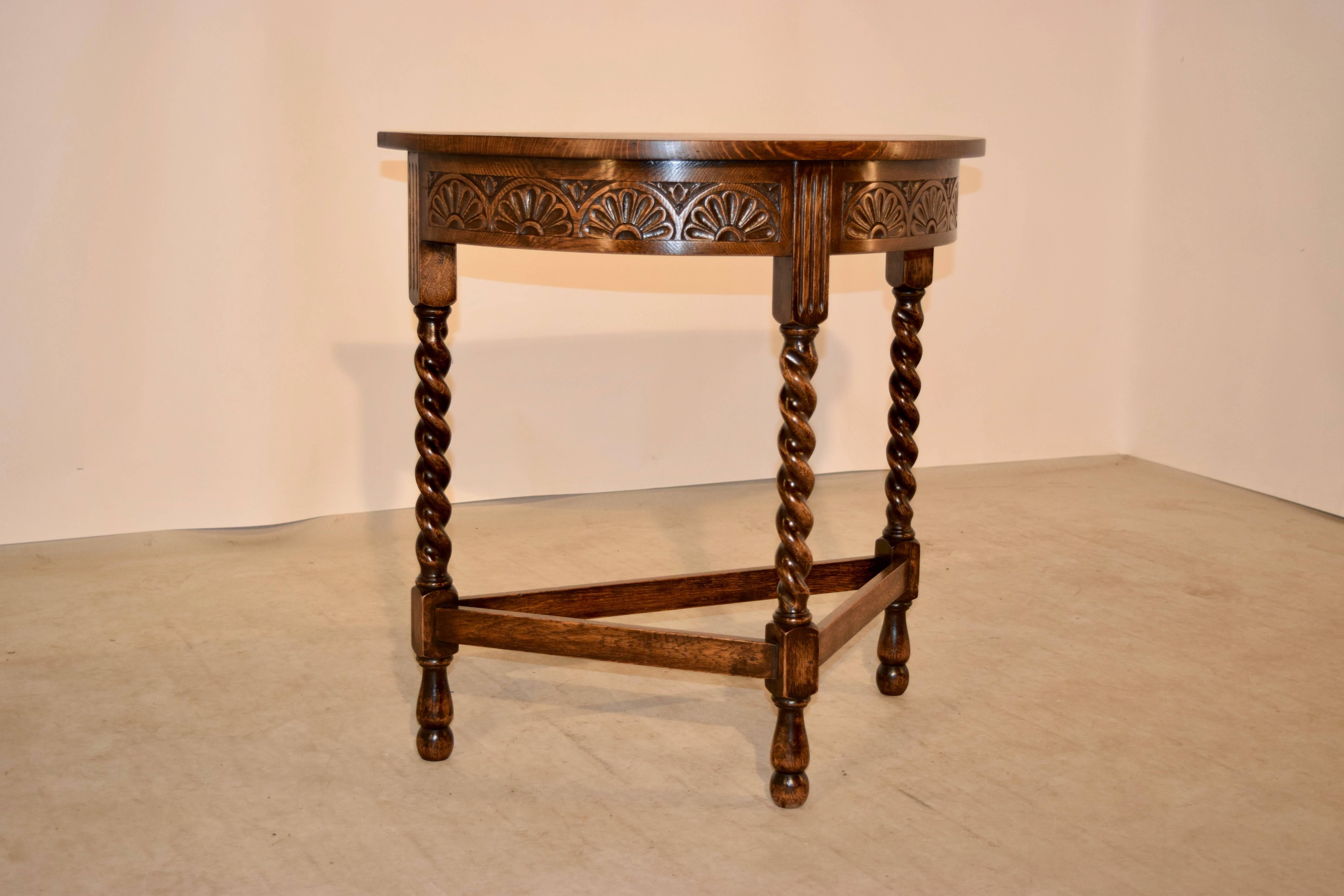 19th century English oak demilune with a hand-carved decorated apron and supported on hand-turned barley twist legs, joined by simple stretchers and supported on hand-turned feet.