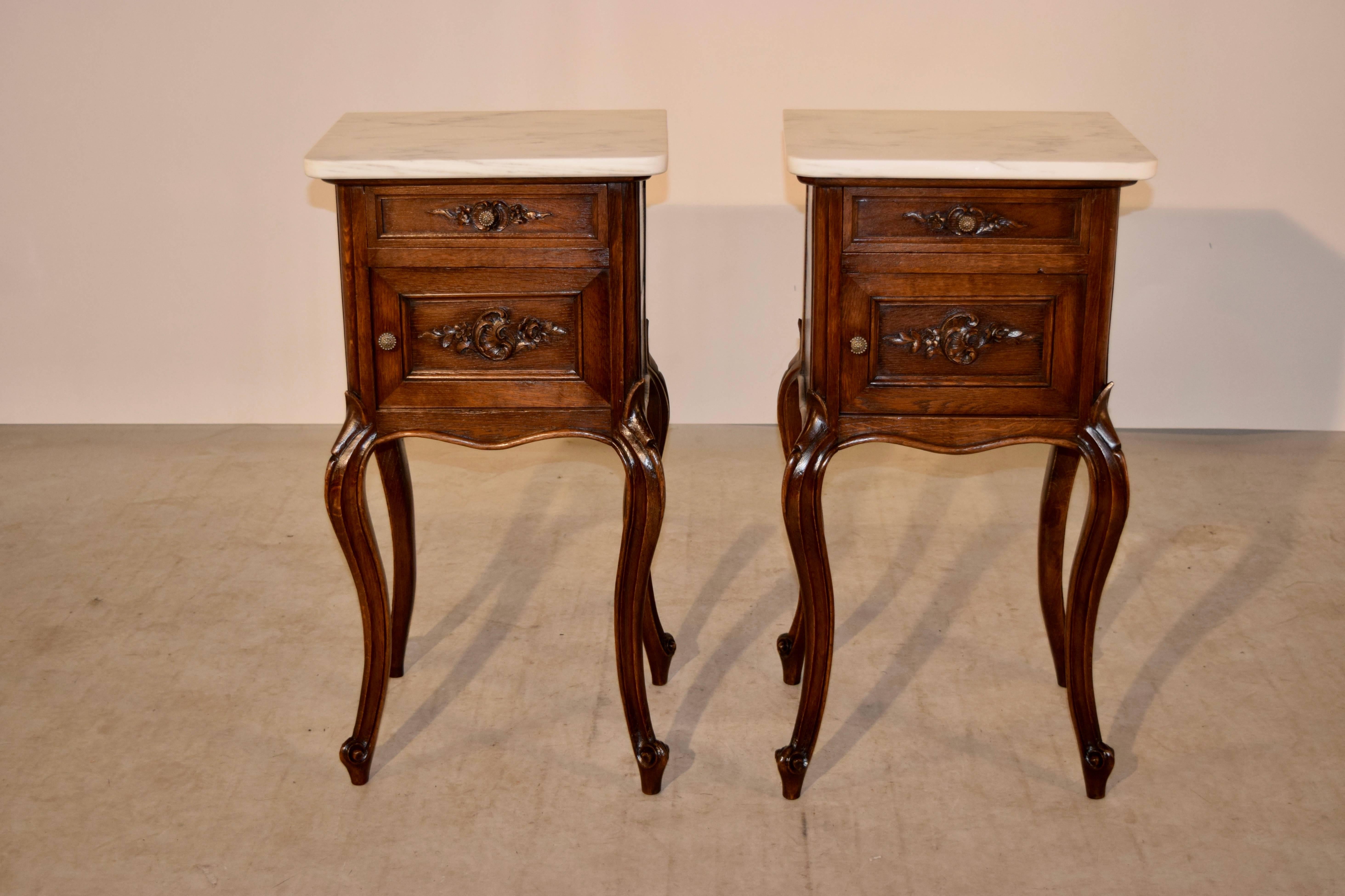 19th century pair of French bedside cabinets made from oak. The tops are marble, with nice neutral veining. There is a single drawer over a single door, which both have lovely hand-carved decoration. The aprons are scalloped on all four sides. The