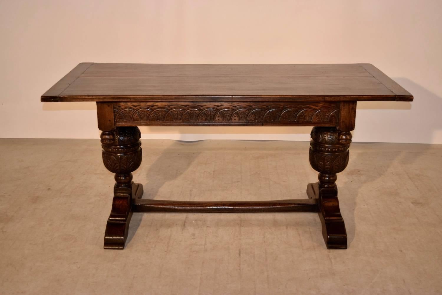 19th century English oak trestle table with a thick two board top with banded ends, following down to a hand-carved decorated apron decorated with hand turned finials and hand carved and turned bulbous legs with wonderful trestle bases joined by a