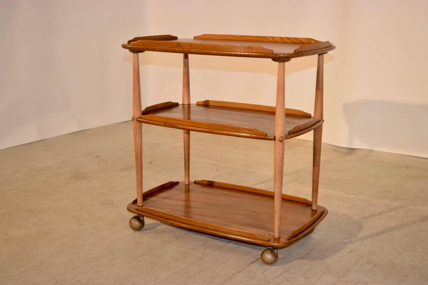 Mid-century elm bar cart from England with wonderfully grained shelves and sleek lines.  Original casters.