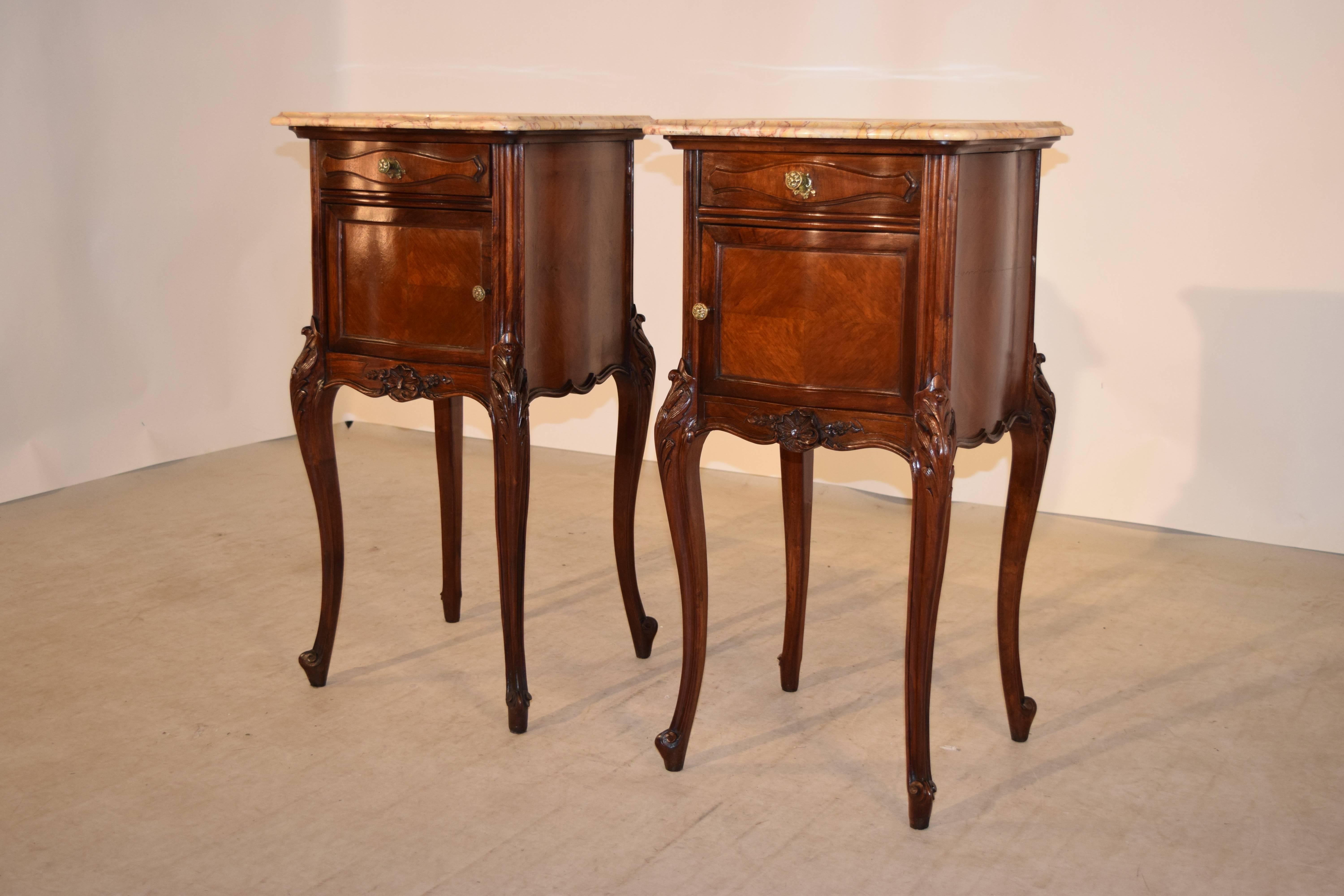 19th Century pair of bedside tables from France.  The tops are removable and are made of lovely grained marble with rich tones of reds and tans, following down to serpentine shaped cases made of mahogany, raised on hand carved cabriole legs, ending