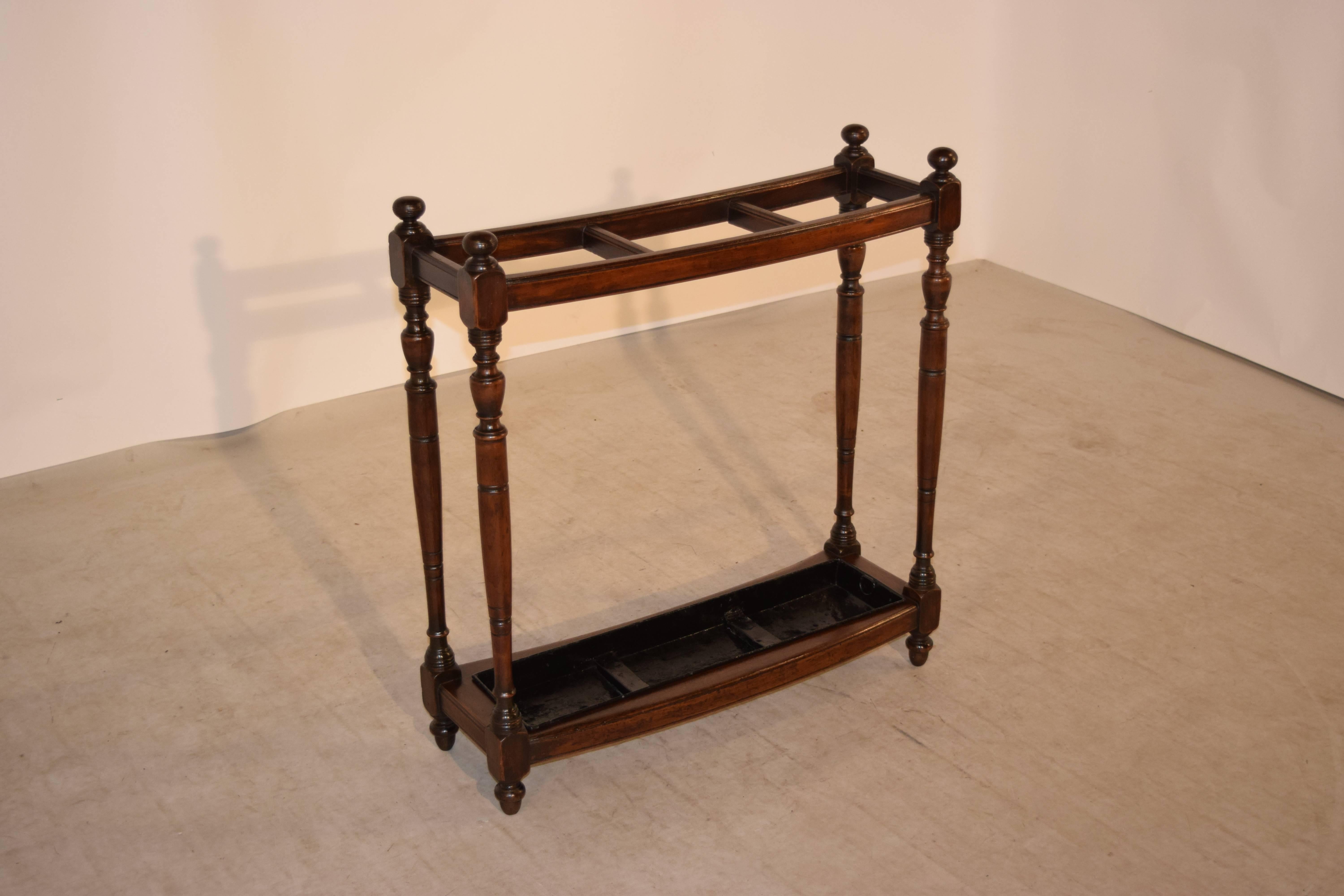 19th Century English curved umbrella stand made from mahogany.  The legs are hand turned mahogany and are connected at the bottom by a frame which hold a metal tray.