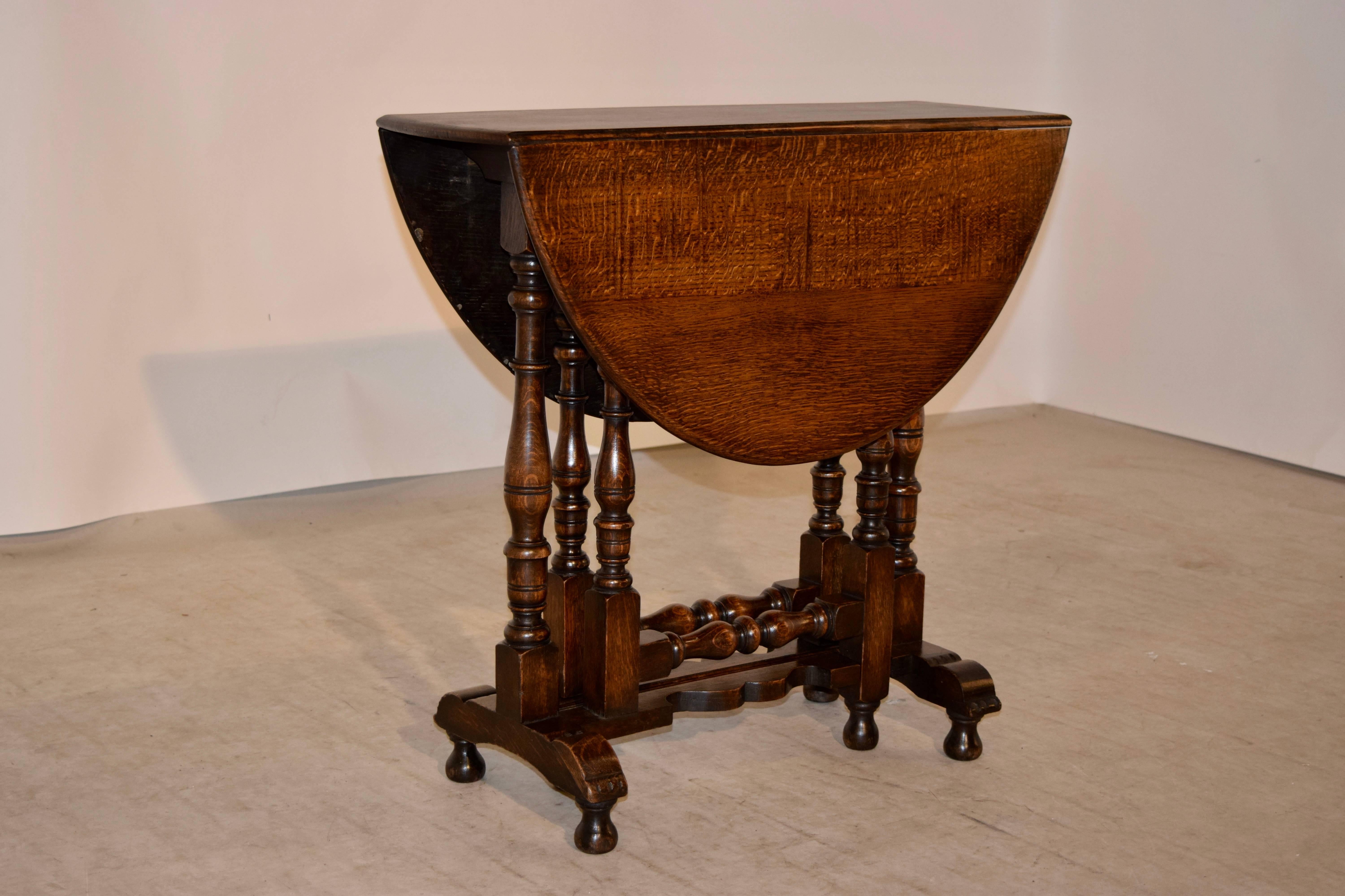 19th century English oak gate leg table with a rounded edge around the top following down to scalloped aprons and supported on hand turned legs and gates joined by a scalloped stretcher and trestles with hand turned feet. Top open measures 34.75 x