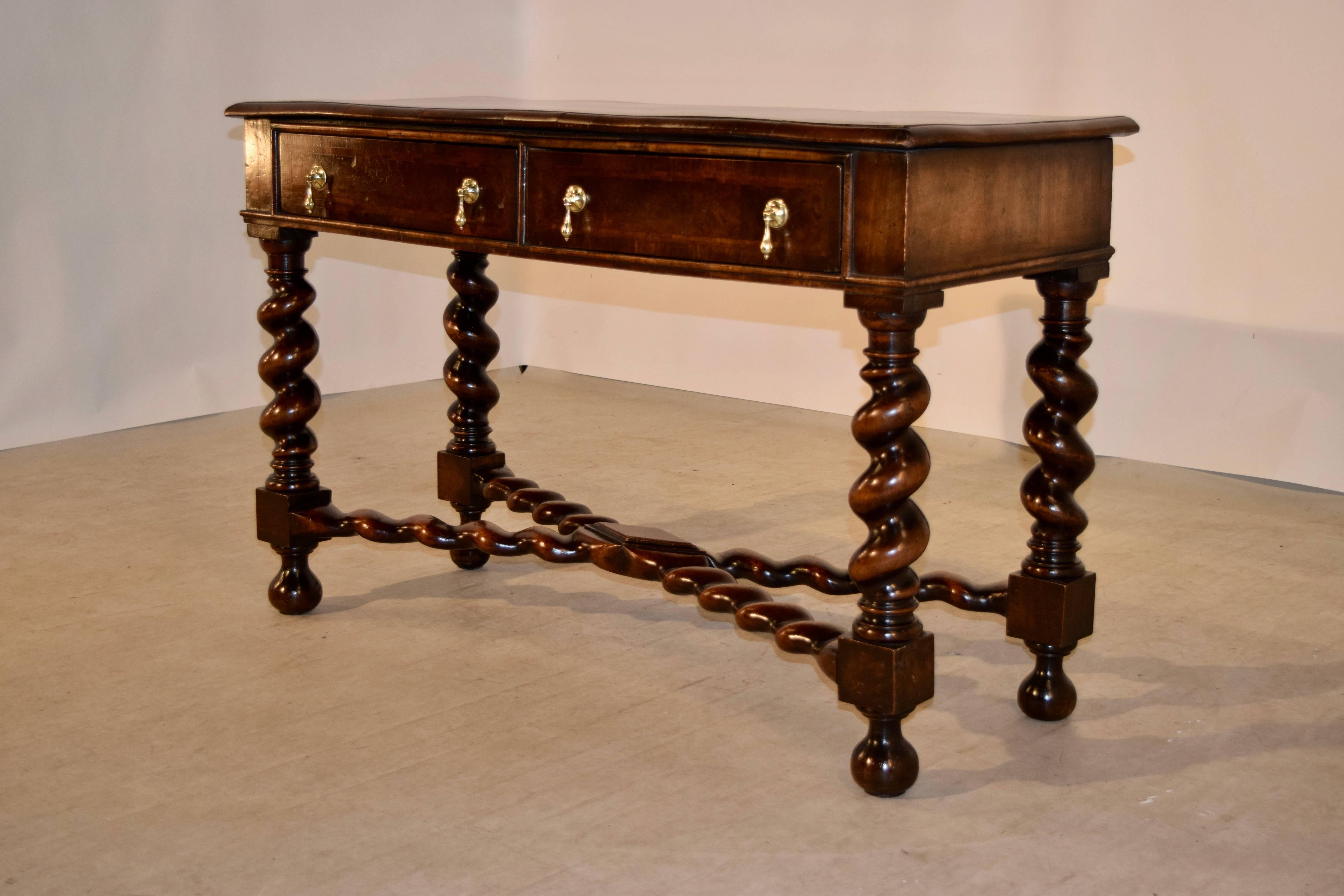 19th century walnut console from England. The top is banded and has a bookmatched walnut top and bevelled edge, following down to a simple apron and two drawers in the front. The piece is supported on thick hand-turned barley twist legs, joined by