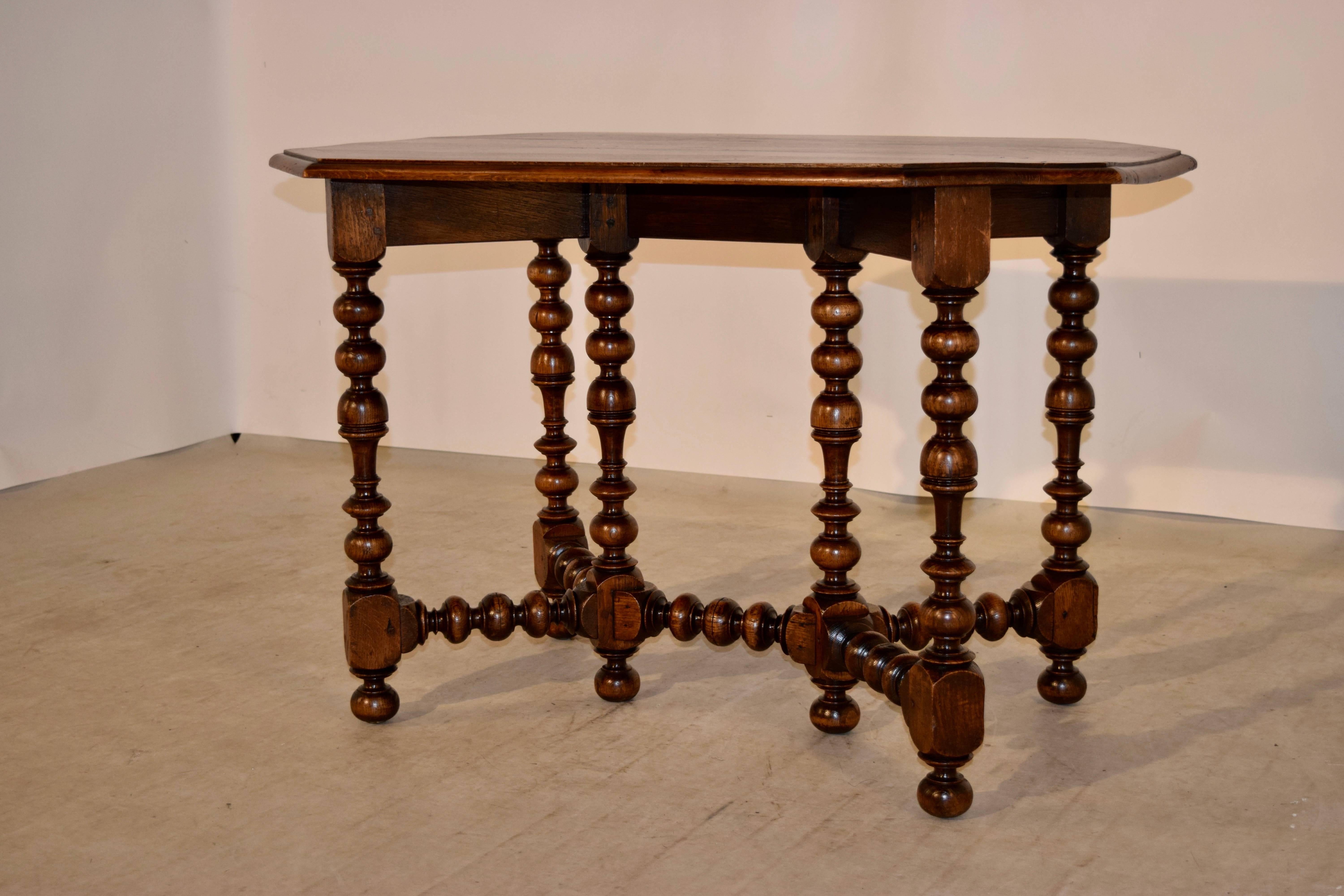 19th century oak table from France. The top is a large octagonal shape with a beveled edge. The apron is simple and follows along with the leg pattern. There are two legs supporting each side of the table, with two central legs. All joined by hand