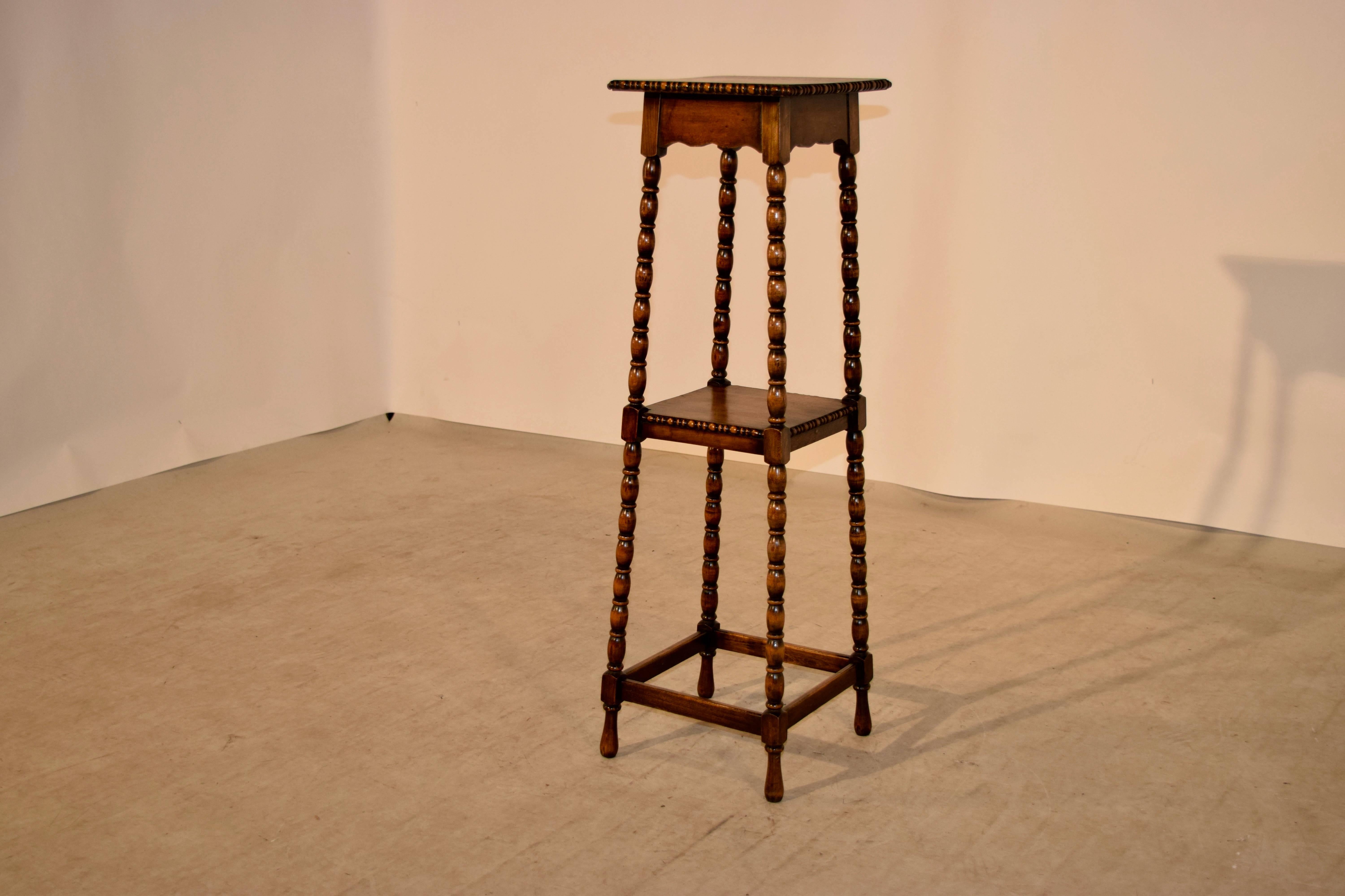 19th century English oak plant stand with a beaded edge around the top, following down to hand turned bob and stop legs. The legs are joined by a central shelf, also with a beaded edge and by simple stretchers at the bottom.