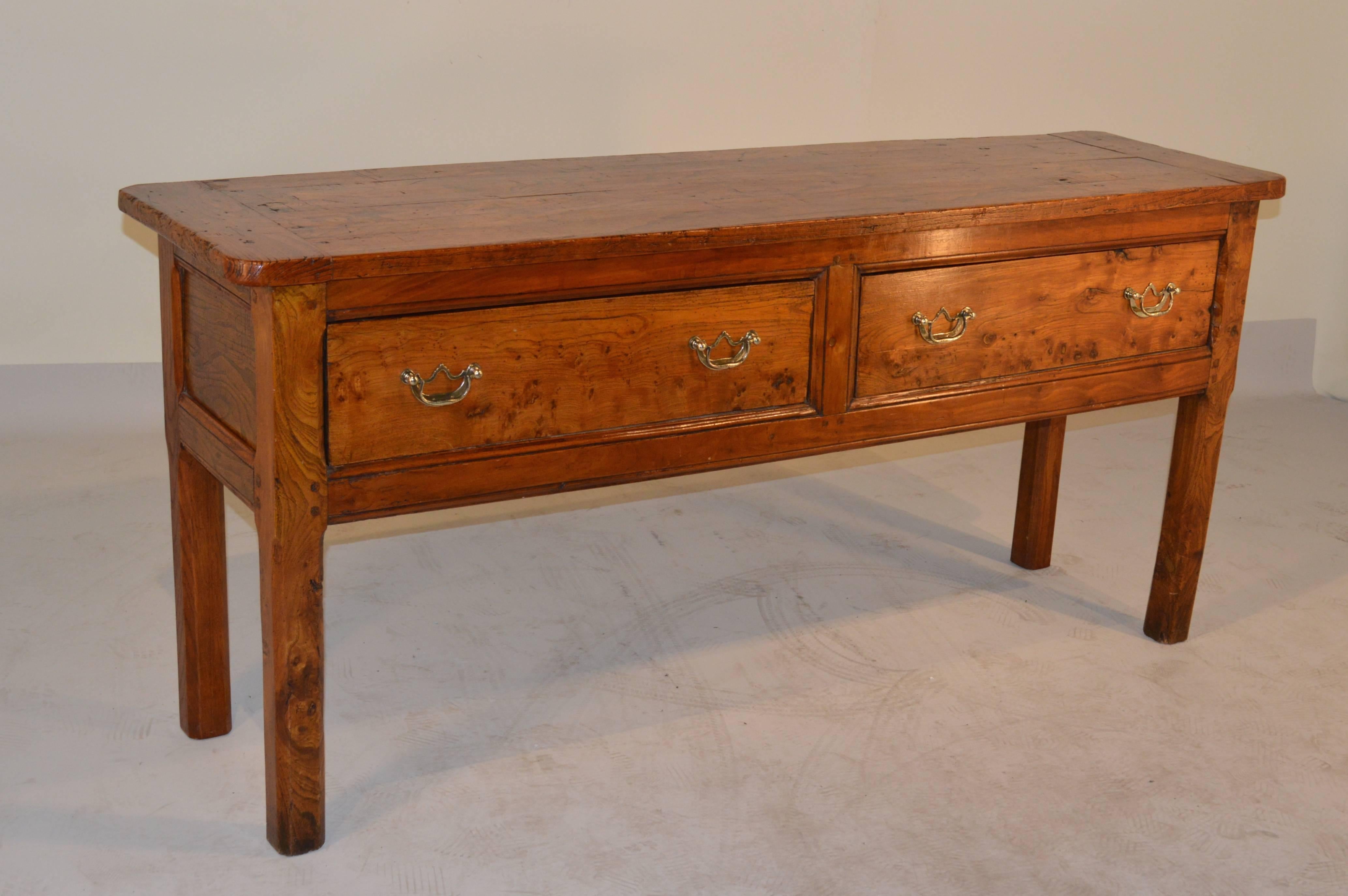 18th century English elm server with a four board top, which is banded on the ends to prevent shrinkage. The apron contains two large drawers, and the piece is panelled on the sides. The piece is raised on chamfered block legs.