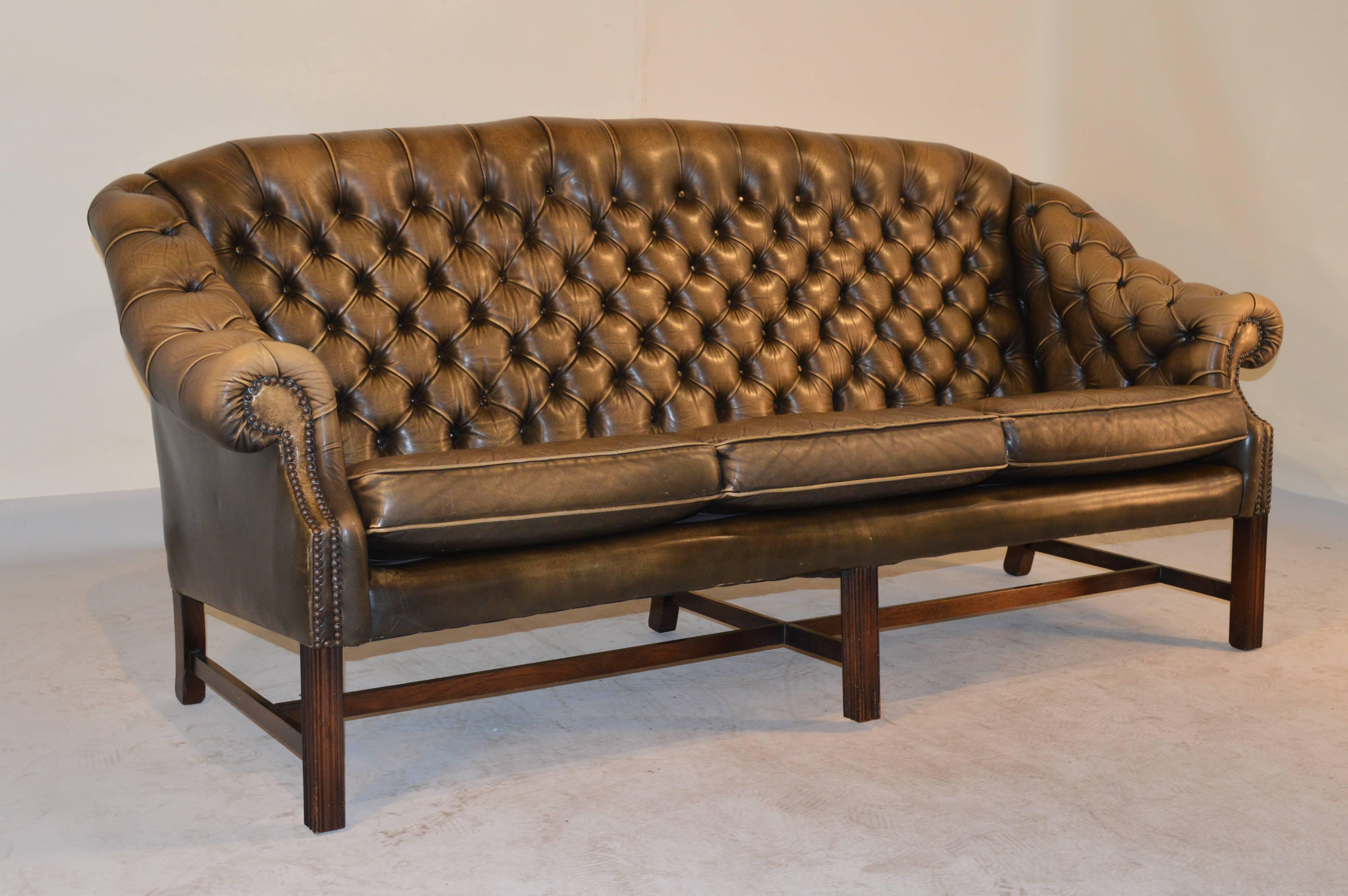 Mid-Century English leather chesterfield sofa with a mahogany frame and lovely old patinated leather upholstery.  It has sloping rolled arms and is wonderfully tufted.  The upholstery is in good condition with age wear.  The seat height measures