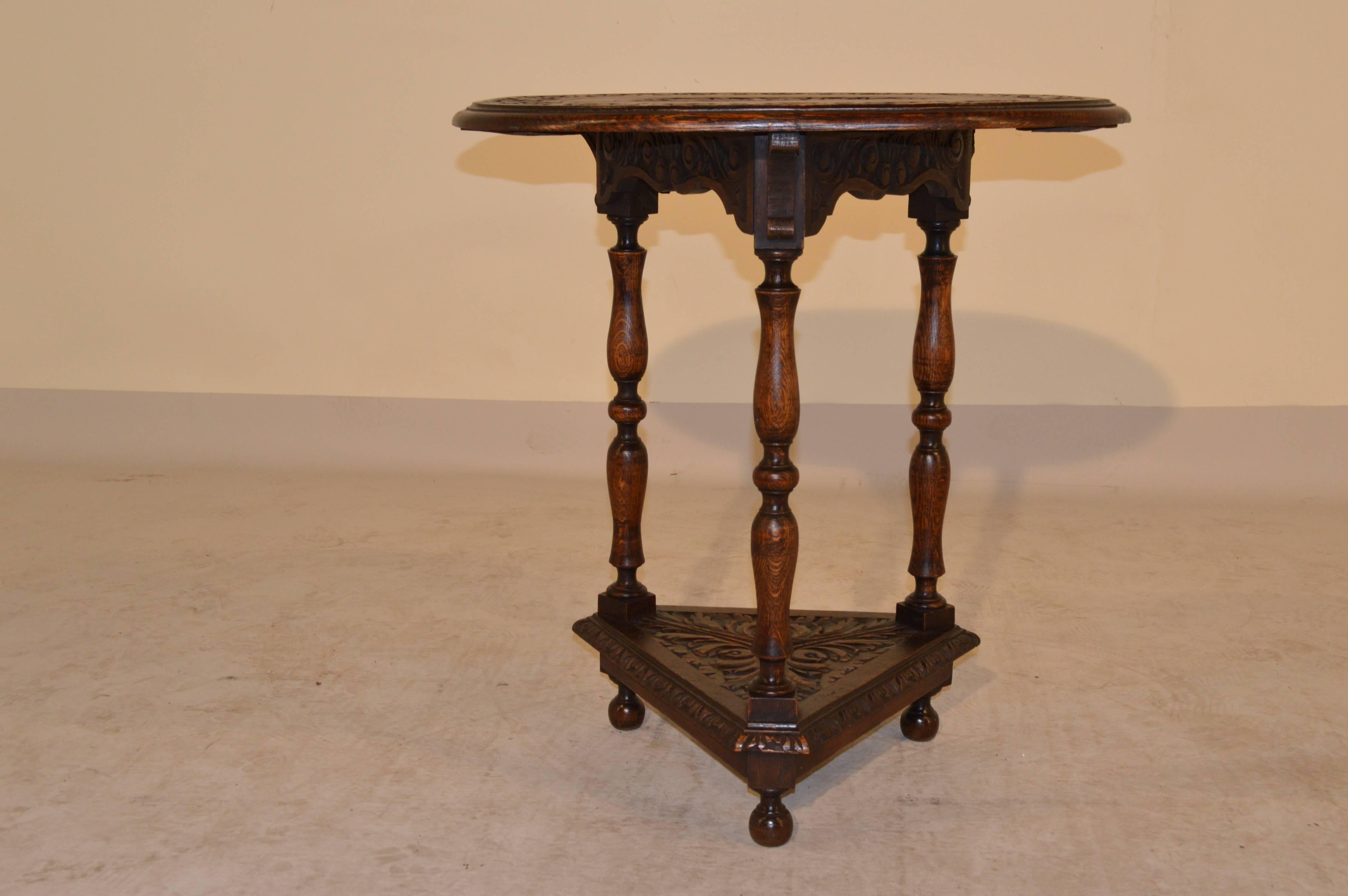 19th Century English oak carved side table with an oval top, which is beveled around the edge and banded with carving, circling a central carved medallion.  The apron is scalloped and carved decorated and follows down to lovely hand turned legs,