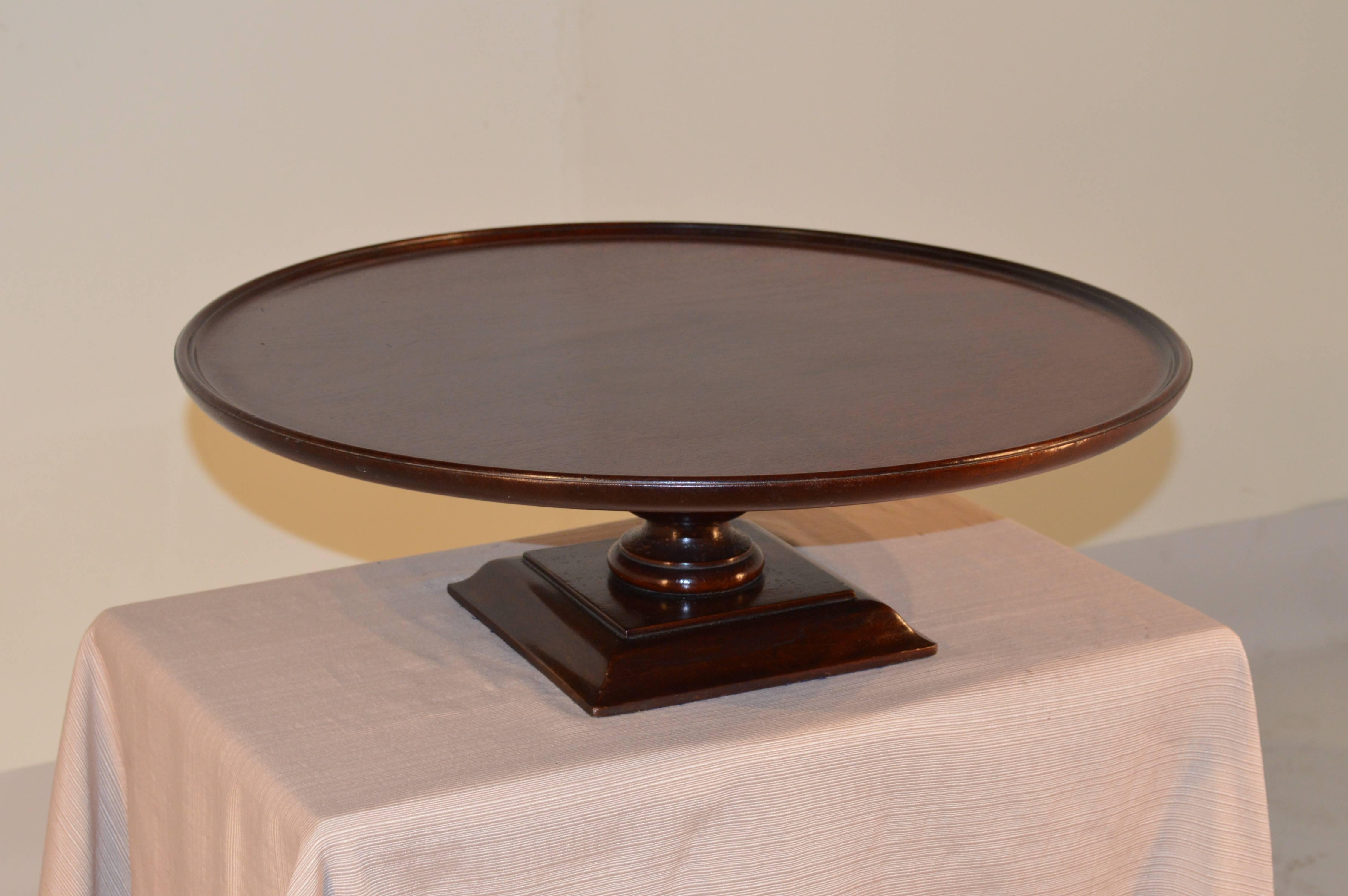 19th century English lazy Susan made from mahogany. The top is a turned dish top and follows down to a turned stem and a square base with molded edges. The contrast between the square base and round top is unusual and interesting.