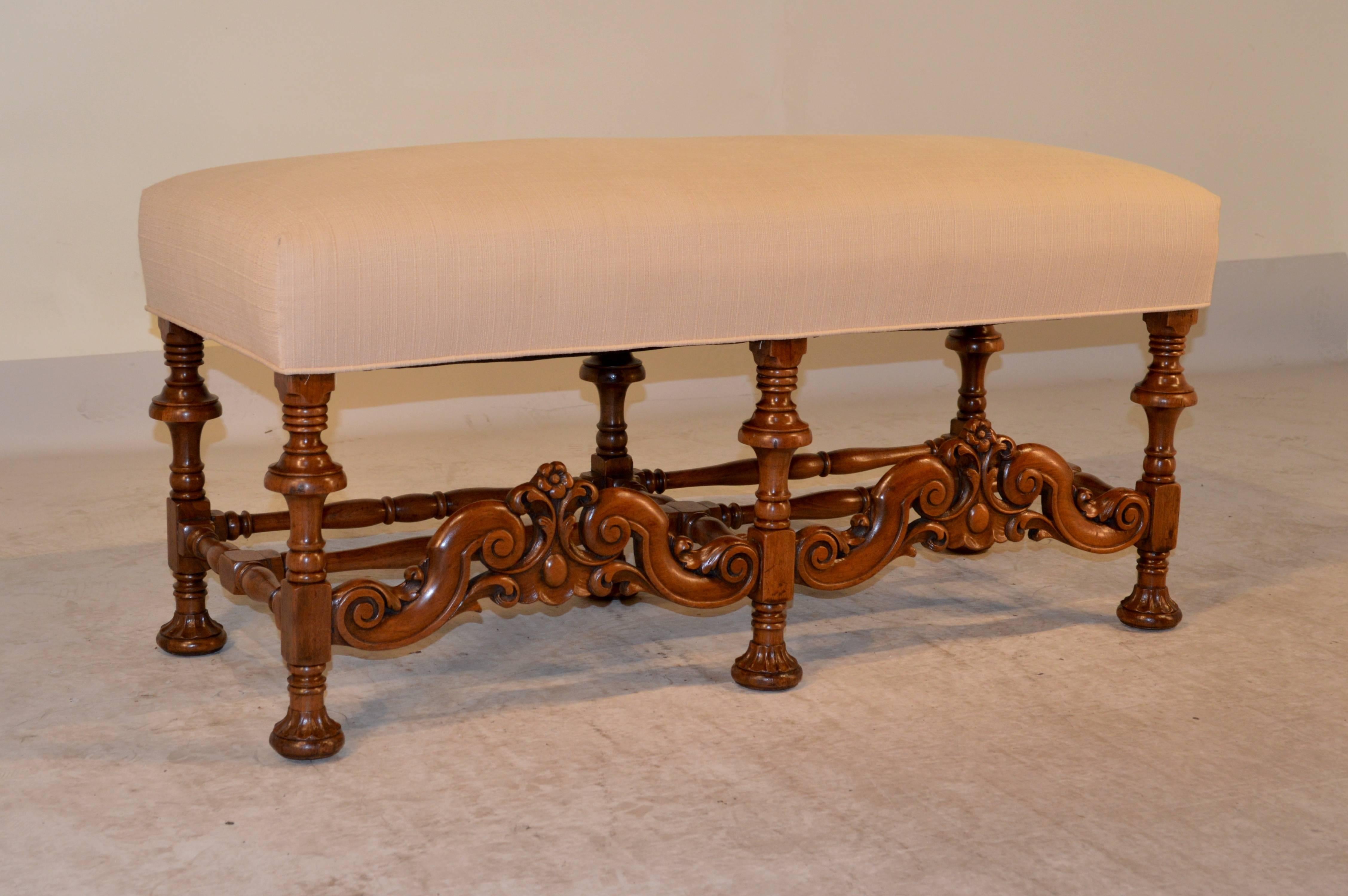 19th Century English carved bench made from walnut with a newly upholstered linen top.  The legs are wonderfully detailed hand turned and end in hand carved decorated bun feet, joined by hand turned stretchers on the back and sides, and the front