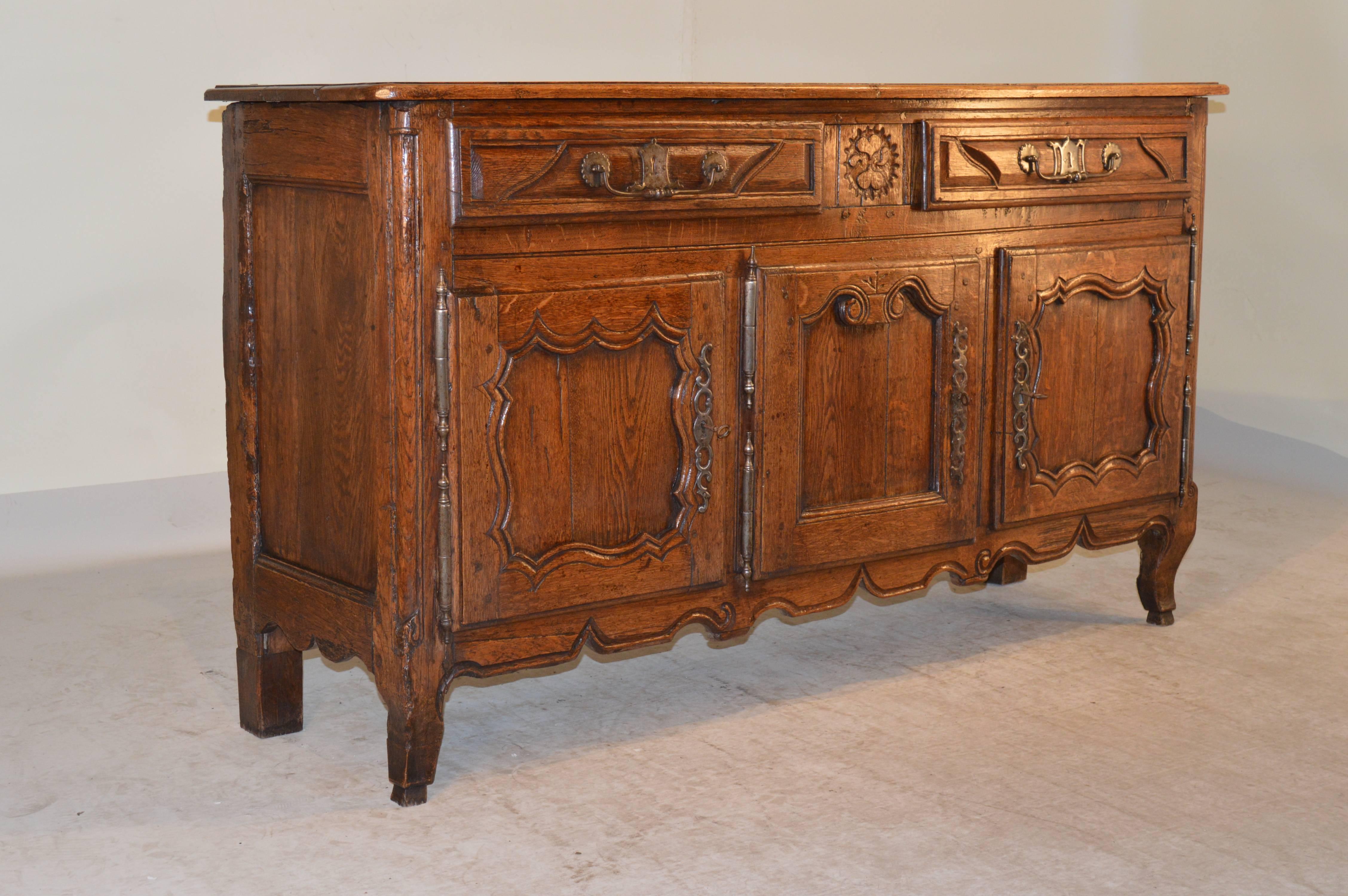 18th century French buffet made from oak with a three board top which is beveled around the edge. The case contains two drawers, over three doors, which are all hand raised panelled and are decorated with beautifully hand forged hardware. The doors