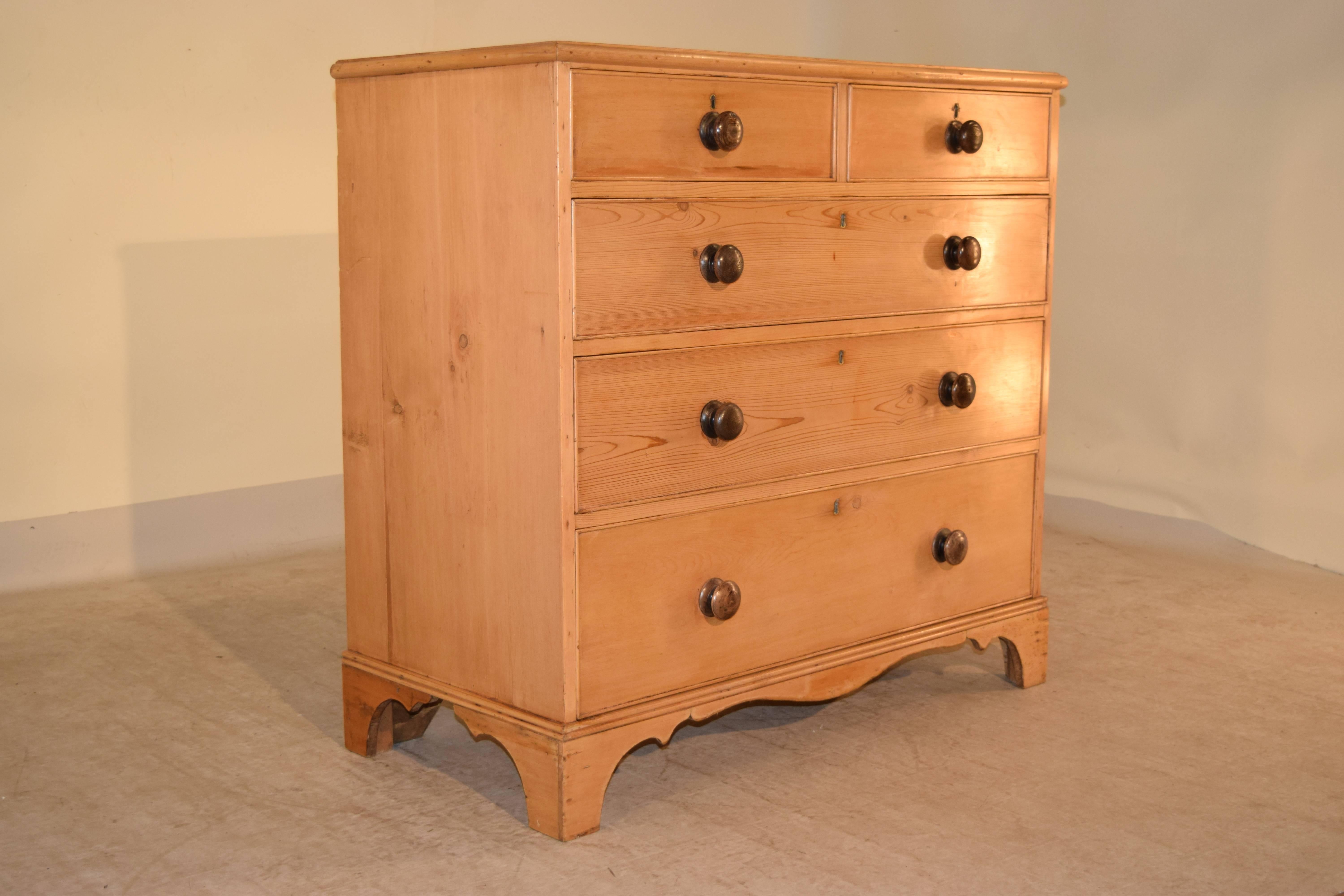 Early 19th century English chest of drawers made from heart pine. The top has a beveled edge following down to two over three drawer configuration. It is raised on wonderful bracket feet with a scalloped skirt.