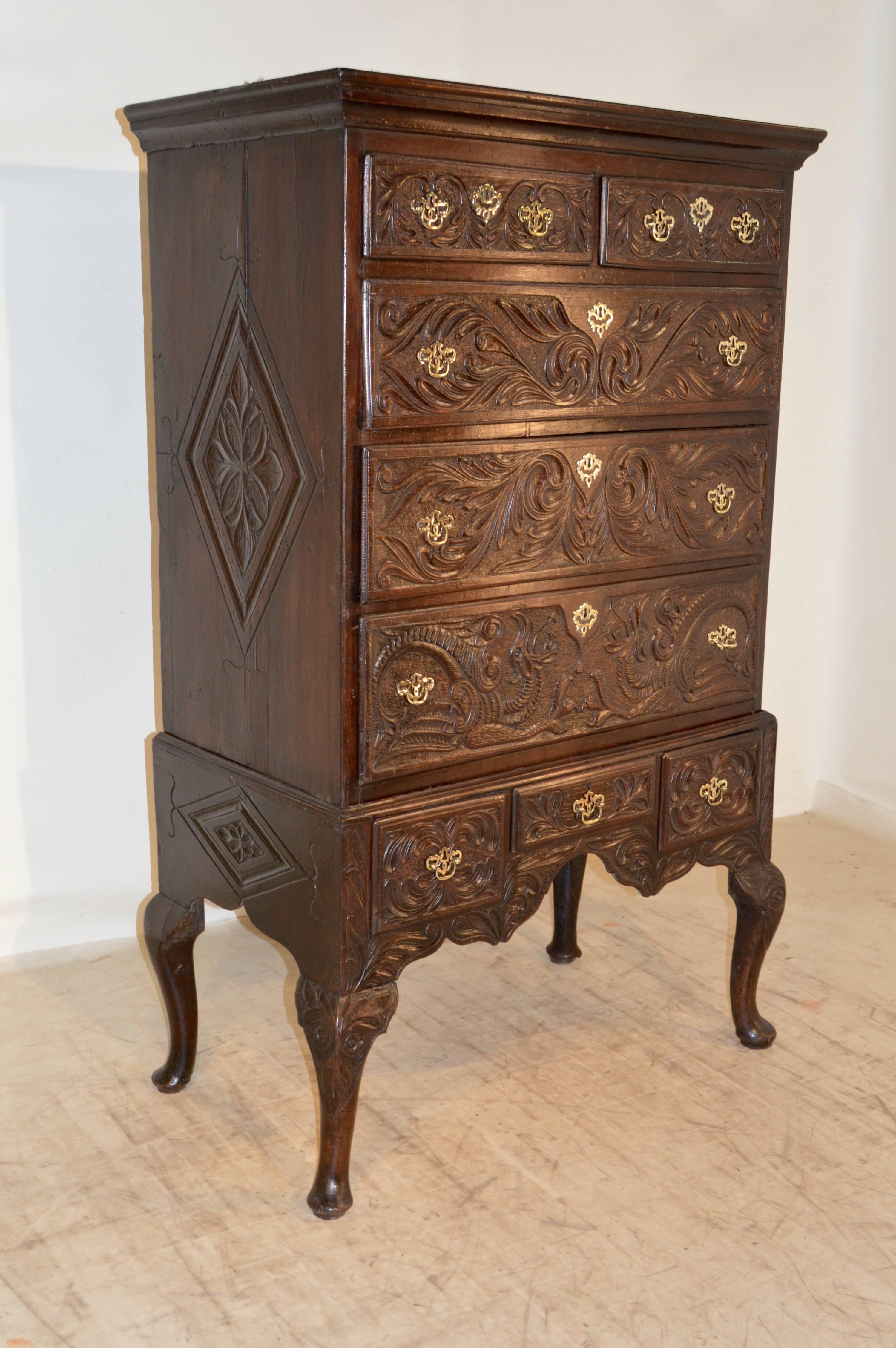 Early 18th century English oak highboy with molded crown around the top, following down to a case with a two over three-drawer configuration, supported on a base with three drawers and hand-turned legs with carved decorated knees, ending in pad