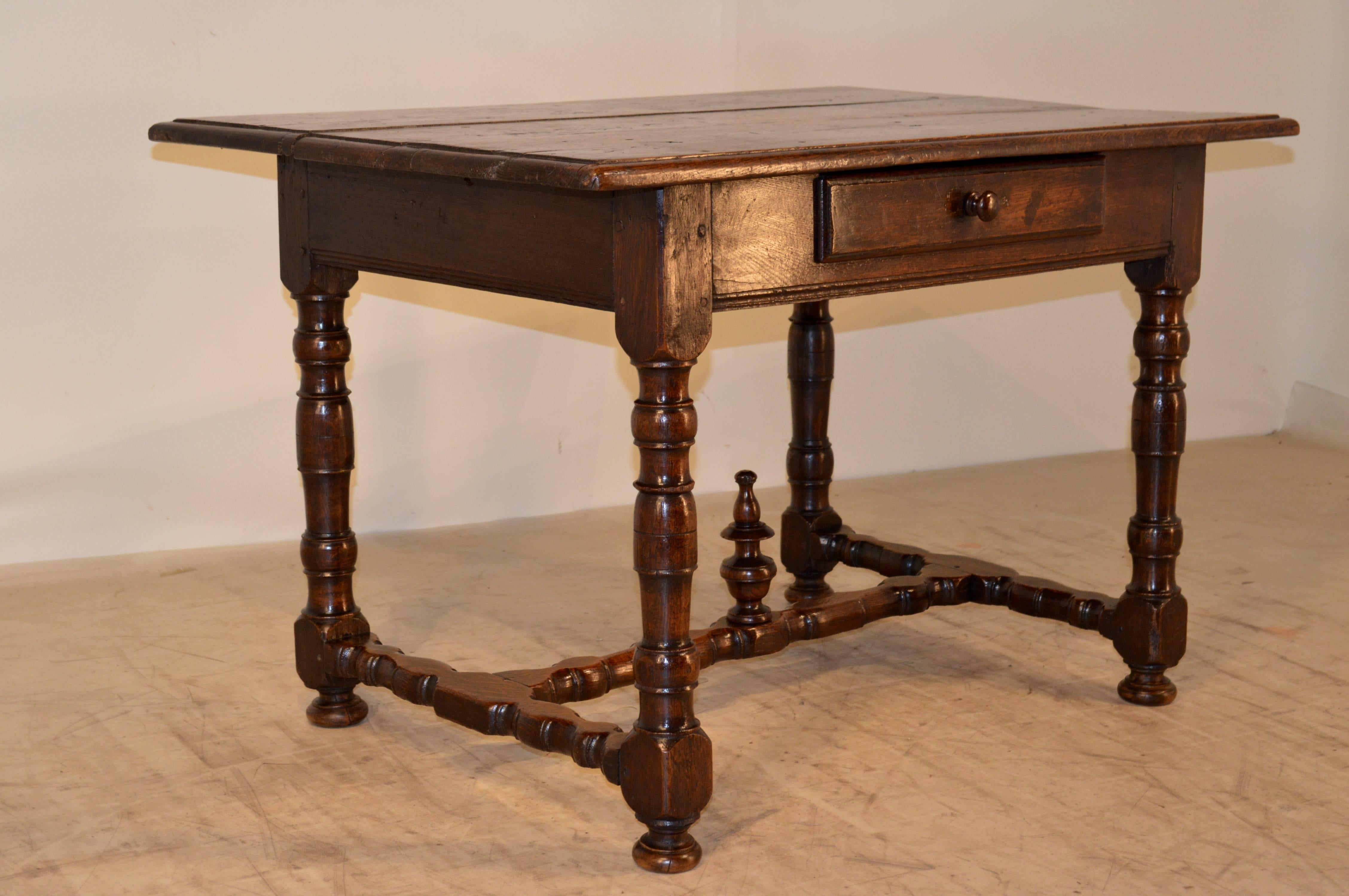 Early 18th century French oak library table. The top is made up of three planks, and has a beveled edge around the top. It has a simple apron containing one drawer and is supported on hand-turned legs, which are joined by hand-turned stretchers,